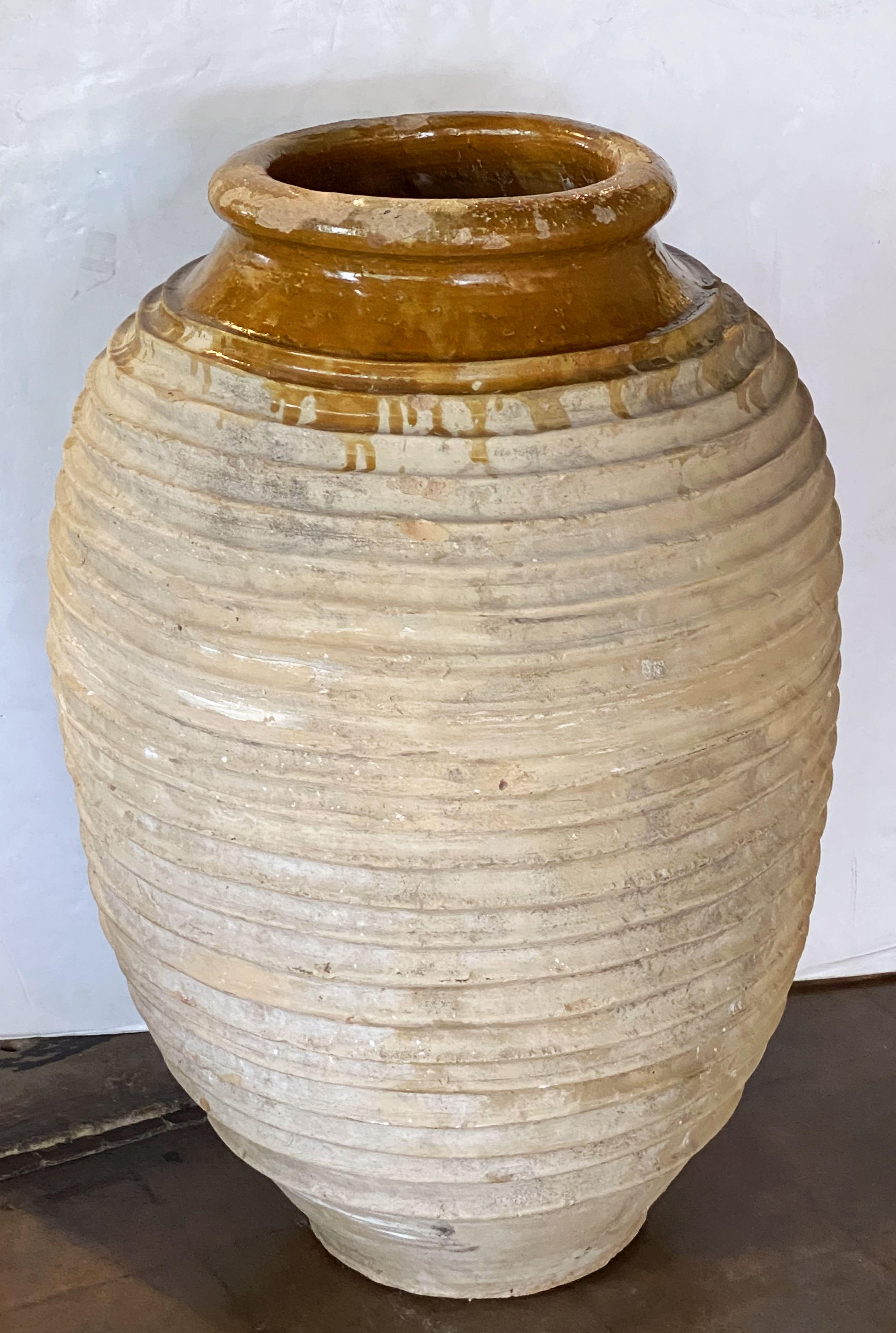 A handsome large Greek garden urn pot (Amphora) or oil jar, featuring a glazed top over a ridged, cylindrical body and functional as an indoor or outdoor garden ornament or planter.

Other similarly styled jars and pots available.

This pot's