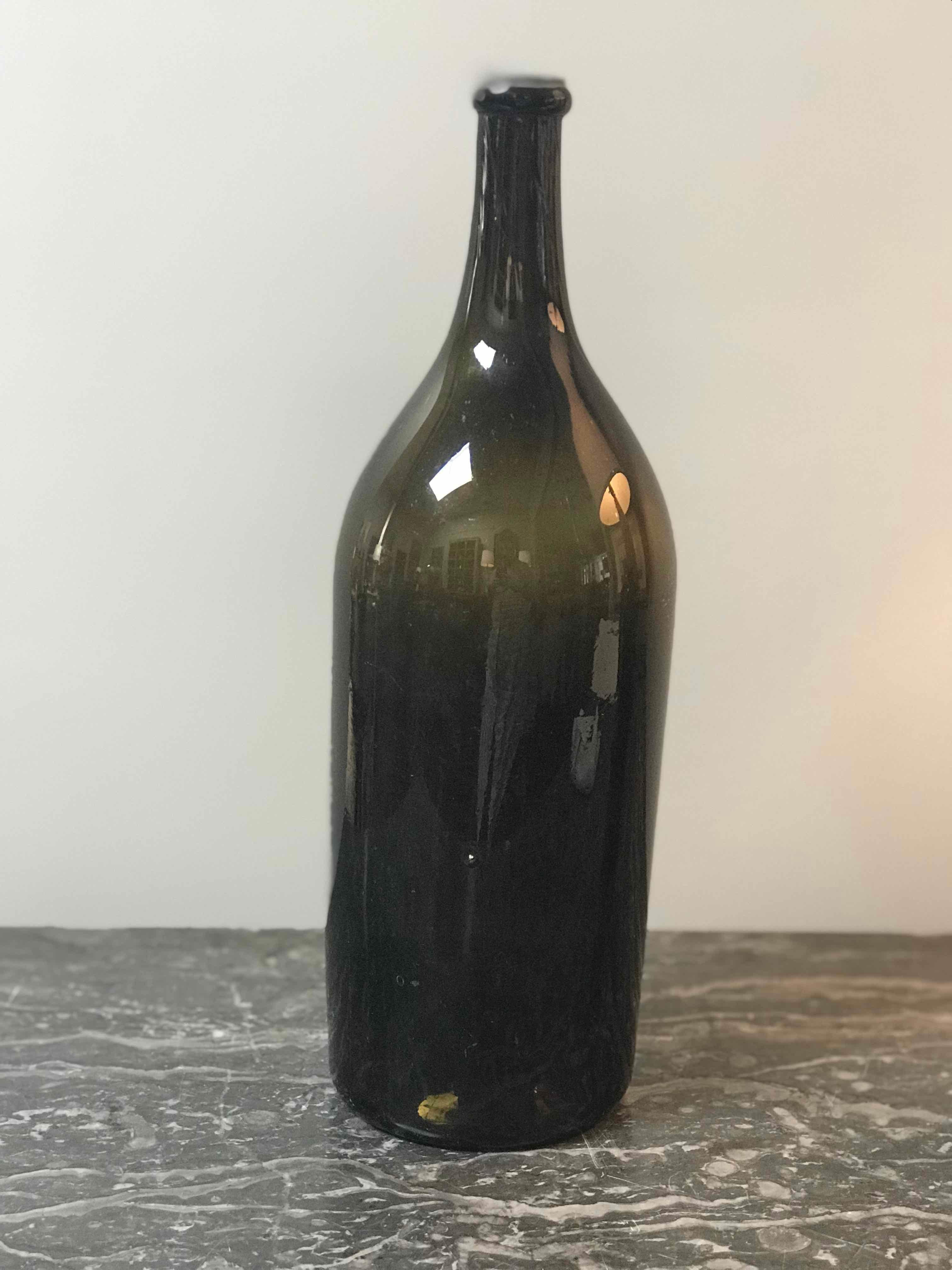 French 19th-century hand-blown glass bottle in beautiful deep olive hue. Rustic and artisanal, this versatile object can be used any number of ways—as a decanter, as a vase, or clustered with other bottles to add height, dimension, and a rich