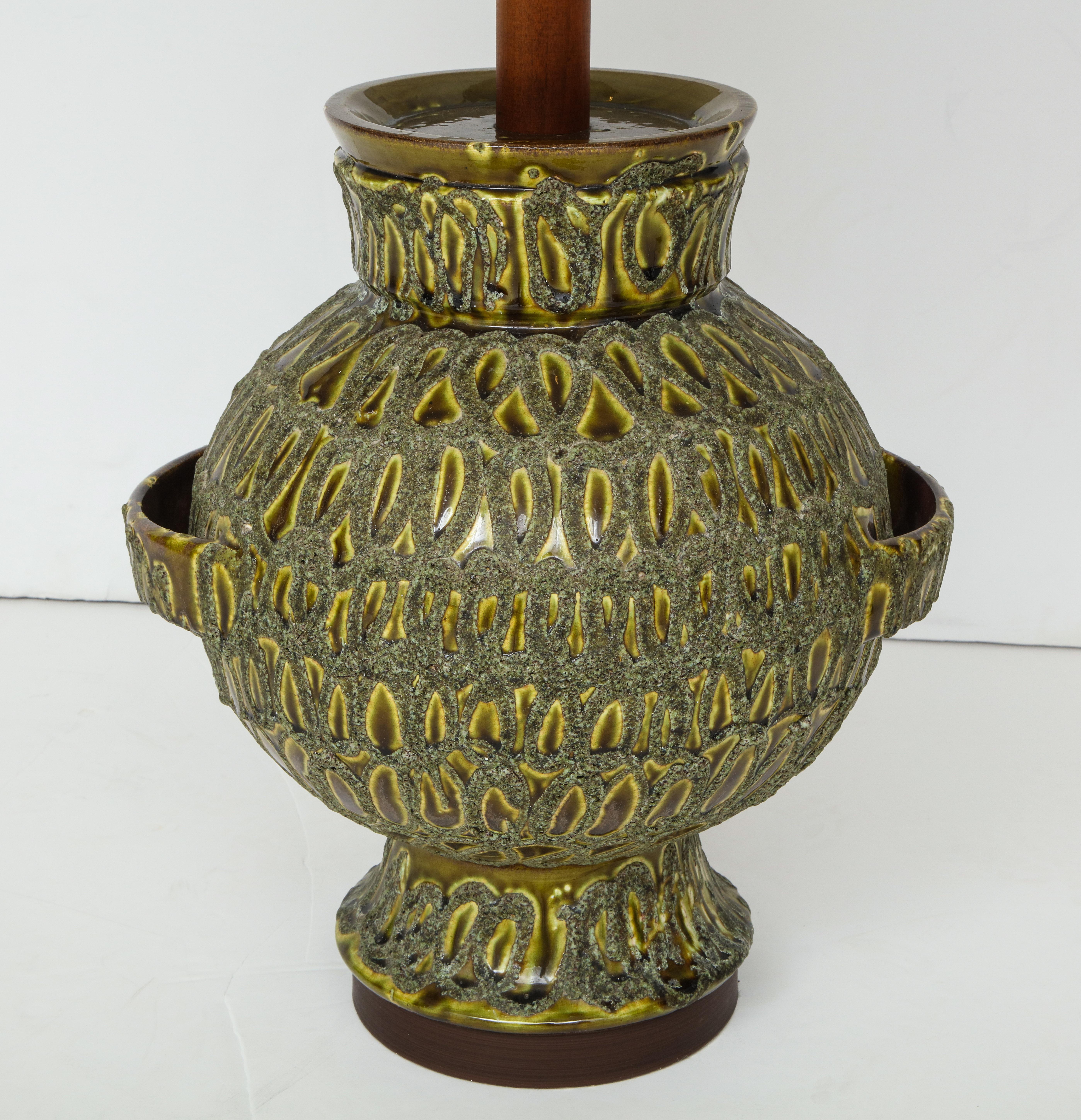 The large bulbous form with a hand notched surface and glazed in tones of light green.