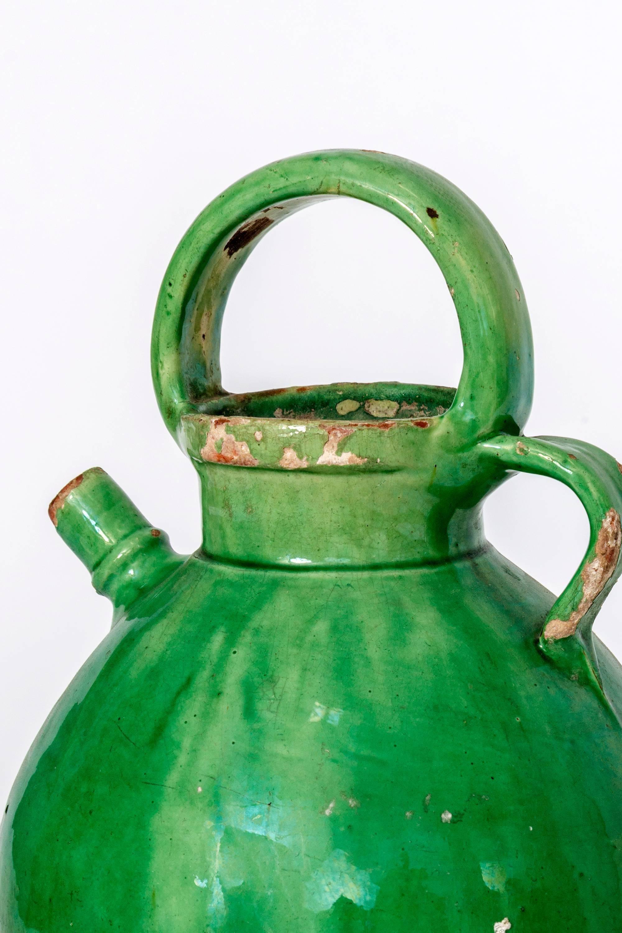 Large green glazed French crockery oil vessel with handles.