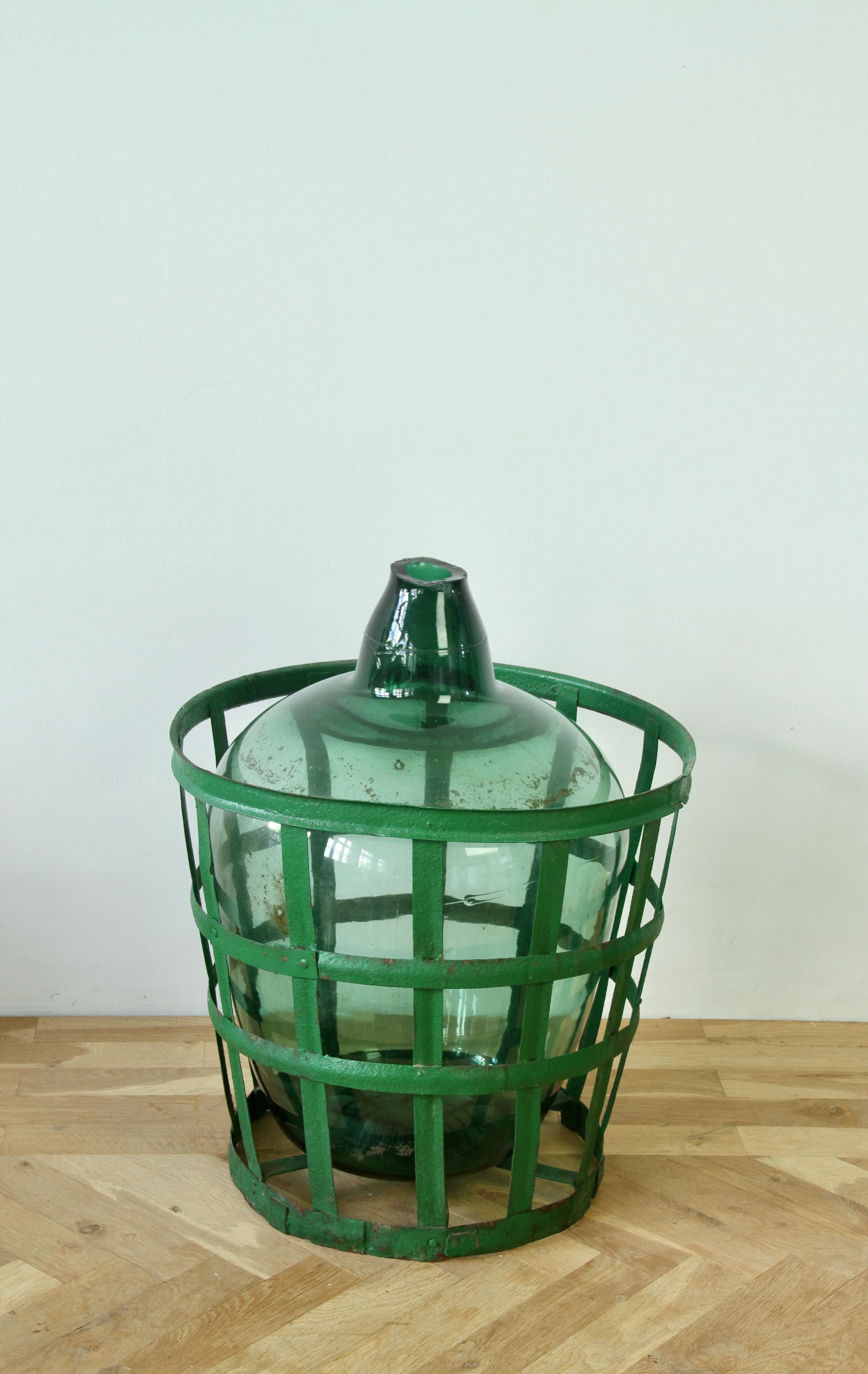 Mid-20th Century Large Green Glass Hungarian Demijohn, Amphora or Vase with Original Iron Basket For Sale