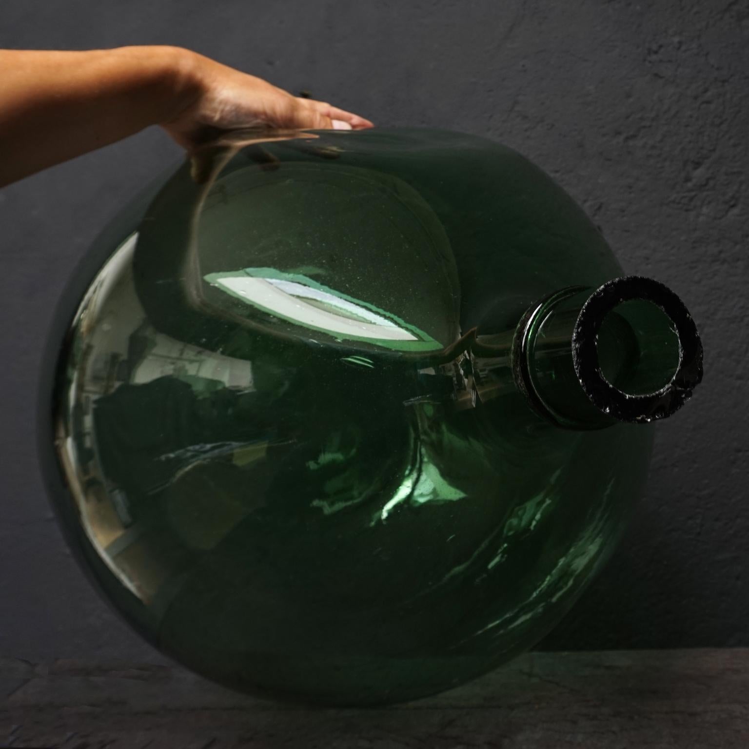 Hand blown in a globular or large ballon form with hand added bottlenecks and cut rim
Wonderful shade of green, hand blown wine bottle, also known as Dame Jeanne, Demijohn, Carboy or Bonbonne bottle with a very nice 'dent' in the glass.

I also