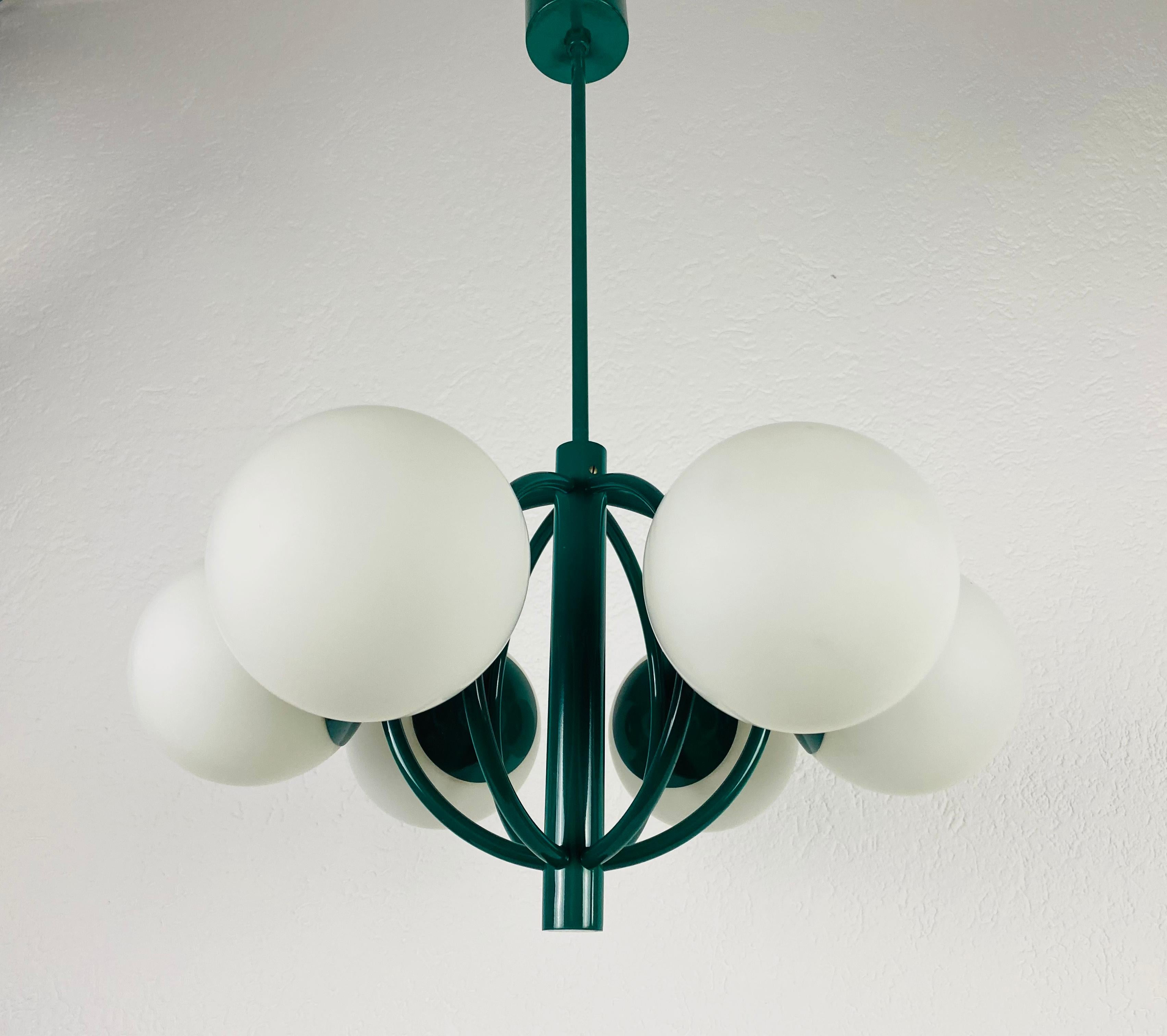 A midcentury chandelier by Kaiser made in Germany in the 1960s. It is fascinating with its Space Age design and eight opaque balls. The white circular body of the light is made of full metal, including the arms. Green bar with green canopy.


The