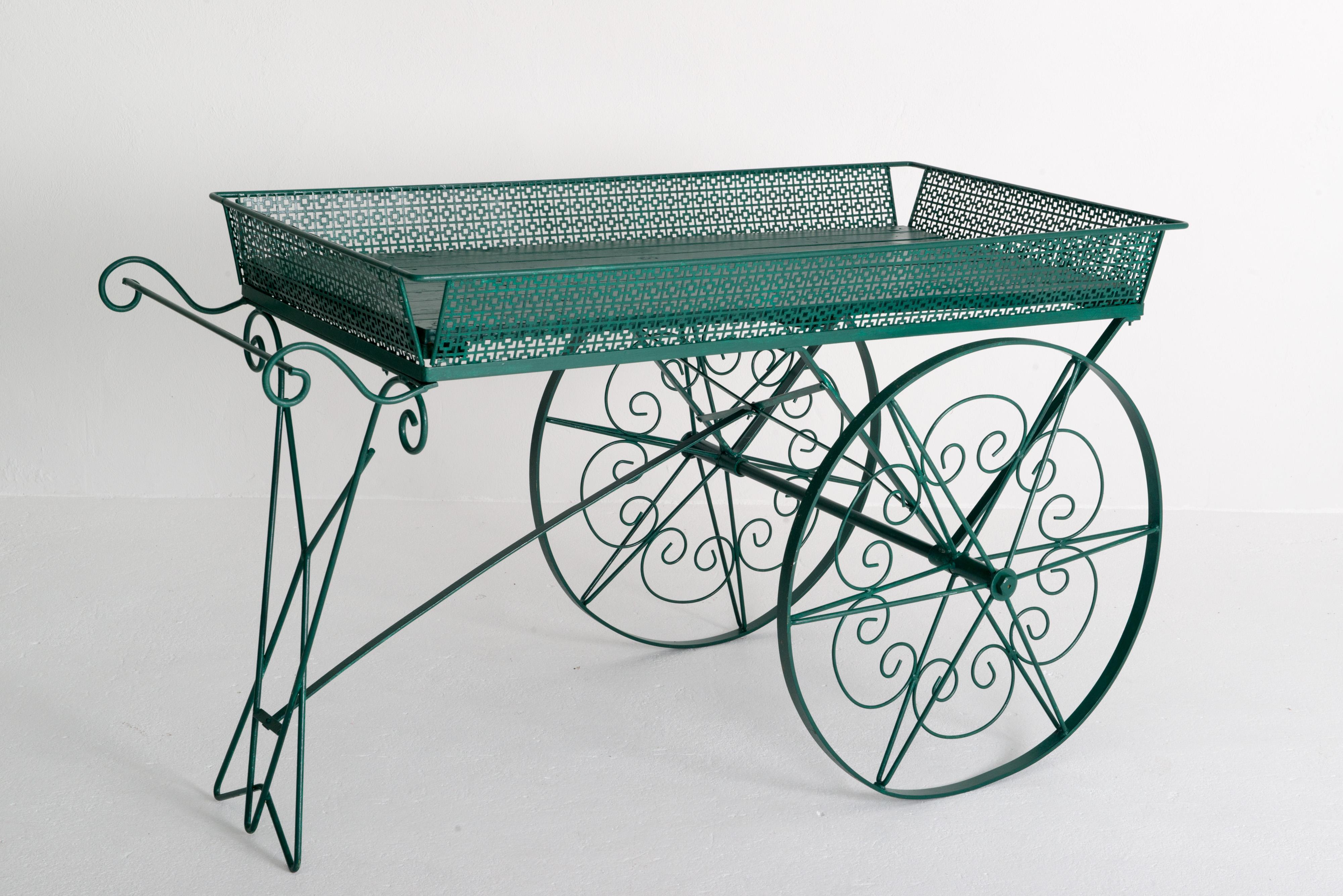 Gran carro de madera pintada de verde y metal para flores de jardín, con grandes ruedas de metal decorativas y funcionales. Este carro es a la vez útil y decorativo. Sería ideal para el jardín o como accesorio en una tienda. Utilice su imaginación.