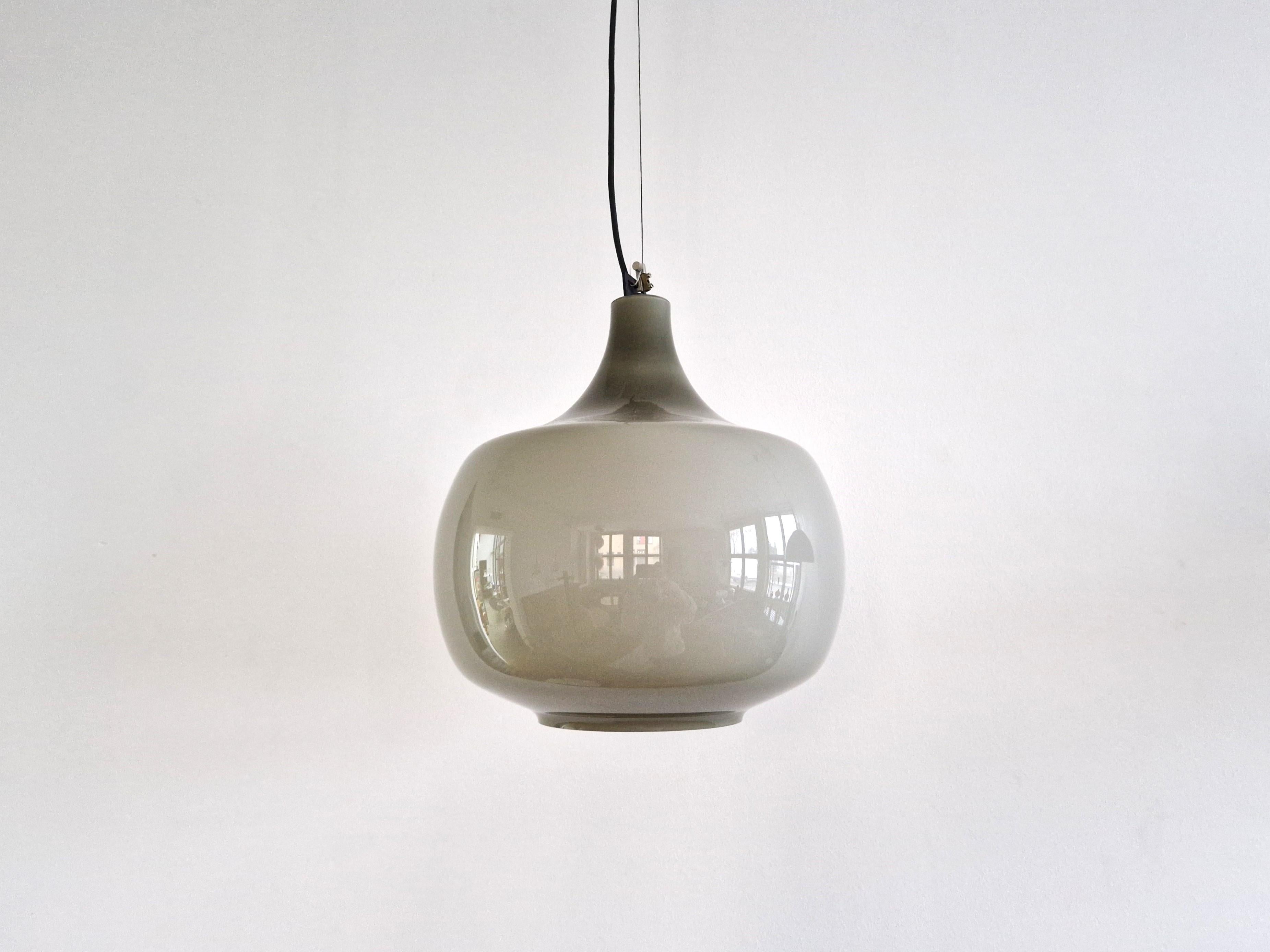 This beautiful glass pendant lamp is a design by Paolo Venini for the company of Venini on the island of Murano. The double glass layer with a white interior and a more grey exterior makes sure that this light gives a soft light when lit. The