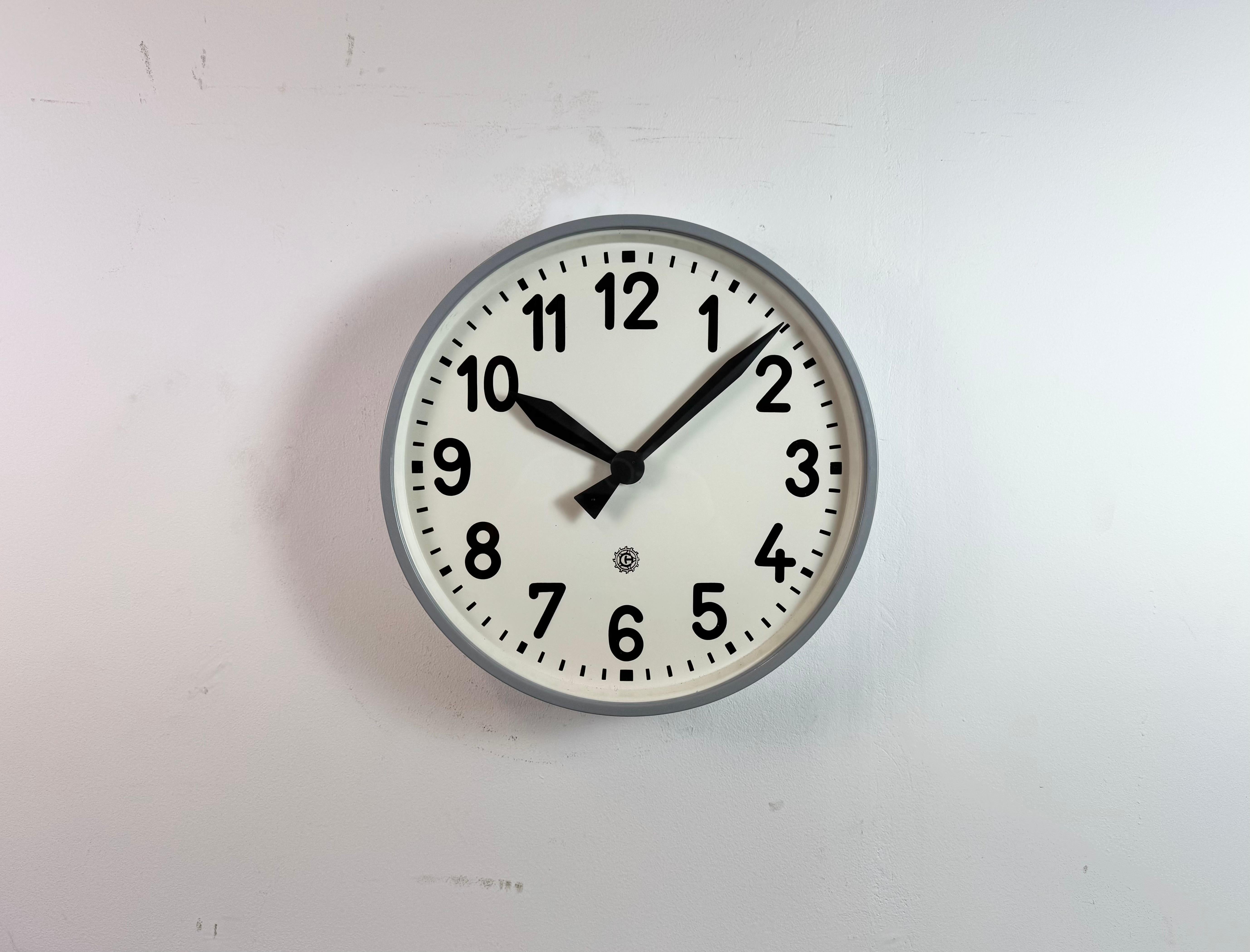 Questo orologio da parete è stato prodotto da Chronotechna nell'ex Cecoslovacchia negli anni Cinquanta. Presenta una struttura in metallo grigio, un quadrante in ferro, lancette in alluminio e un coperchio in vetro trasparente. Il pezzo è stato