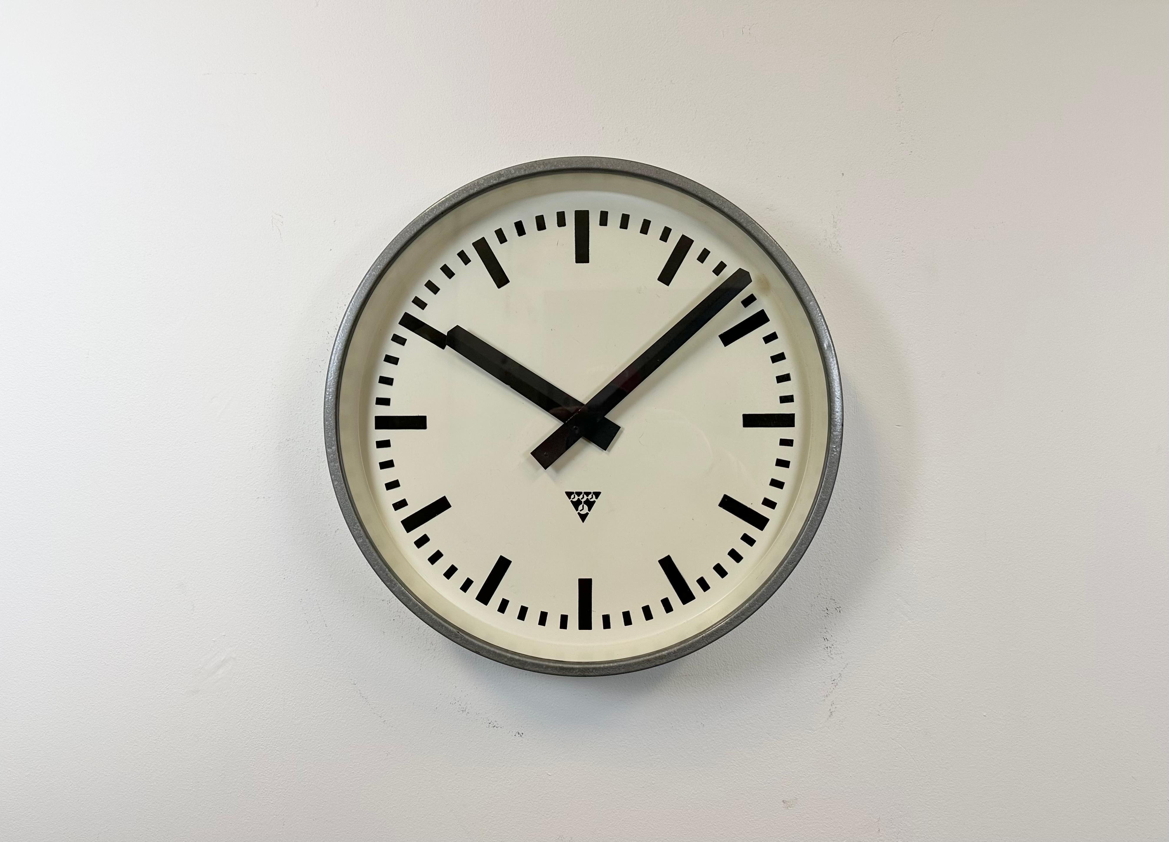 Pragotron wall clock made in former Czechoslovakia during the 1960s. It features a grey hammerpaint metal body, a metal dial and a clear glass cover. The piece has been converted into a battery-powered clockwork and requires only one AA-battery. The