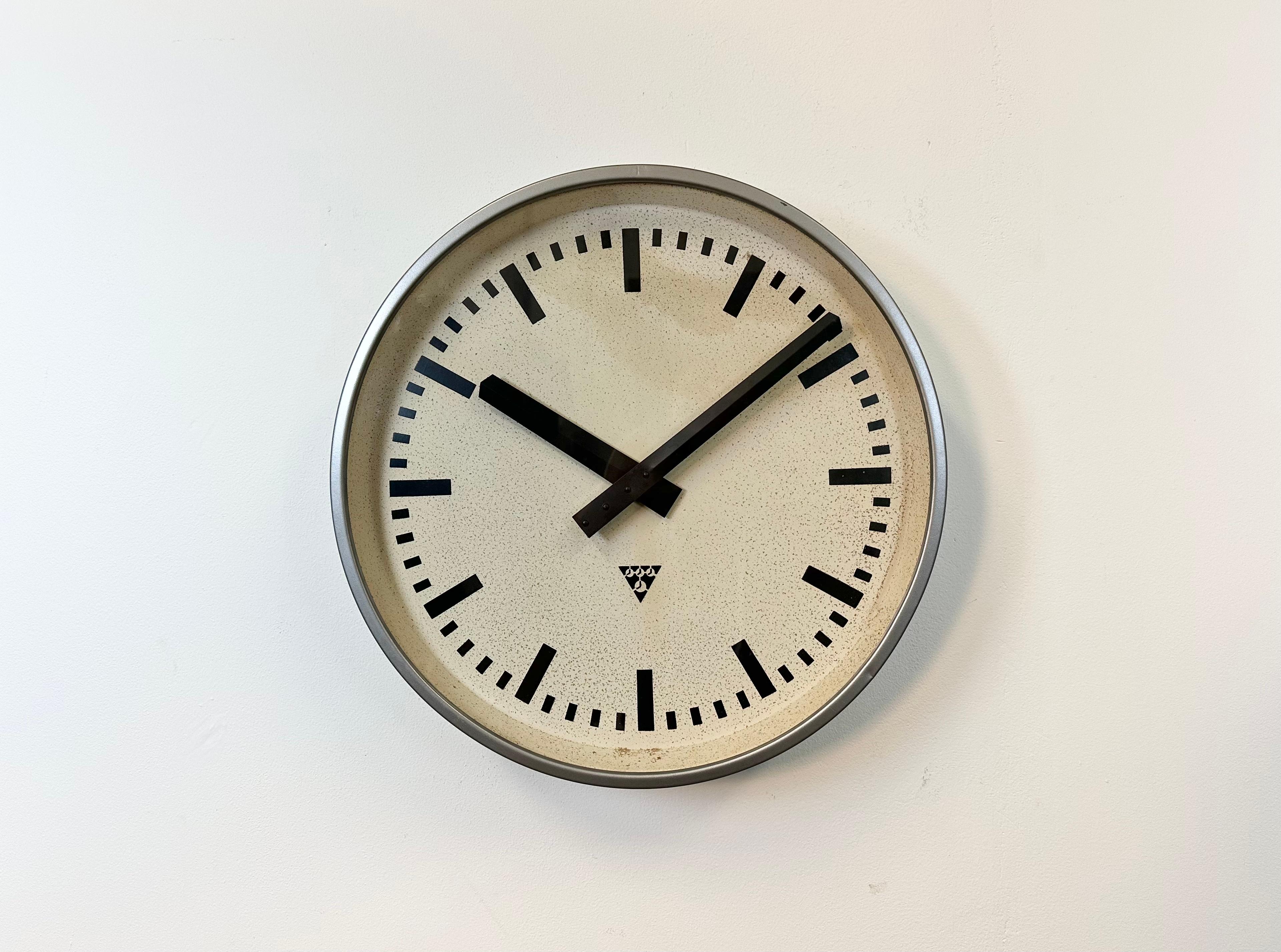 Pragotron wall clock made in former Czechoslovakia during the 1960s. It features a gray metal frame, a metal dial and clear glass cover. The piece has been converted into a battery-powered clockwork and requires only one AA-battery. The diameter of