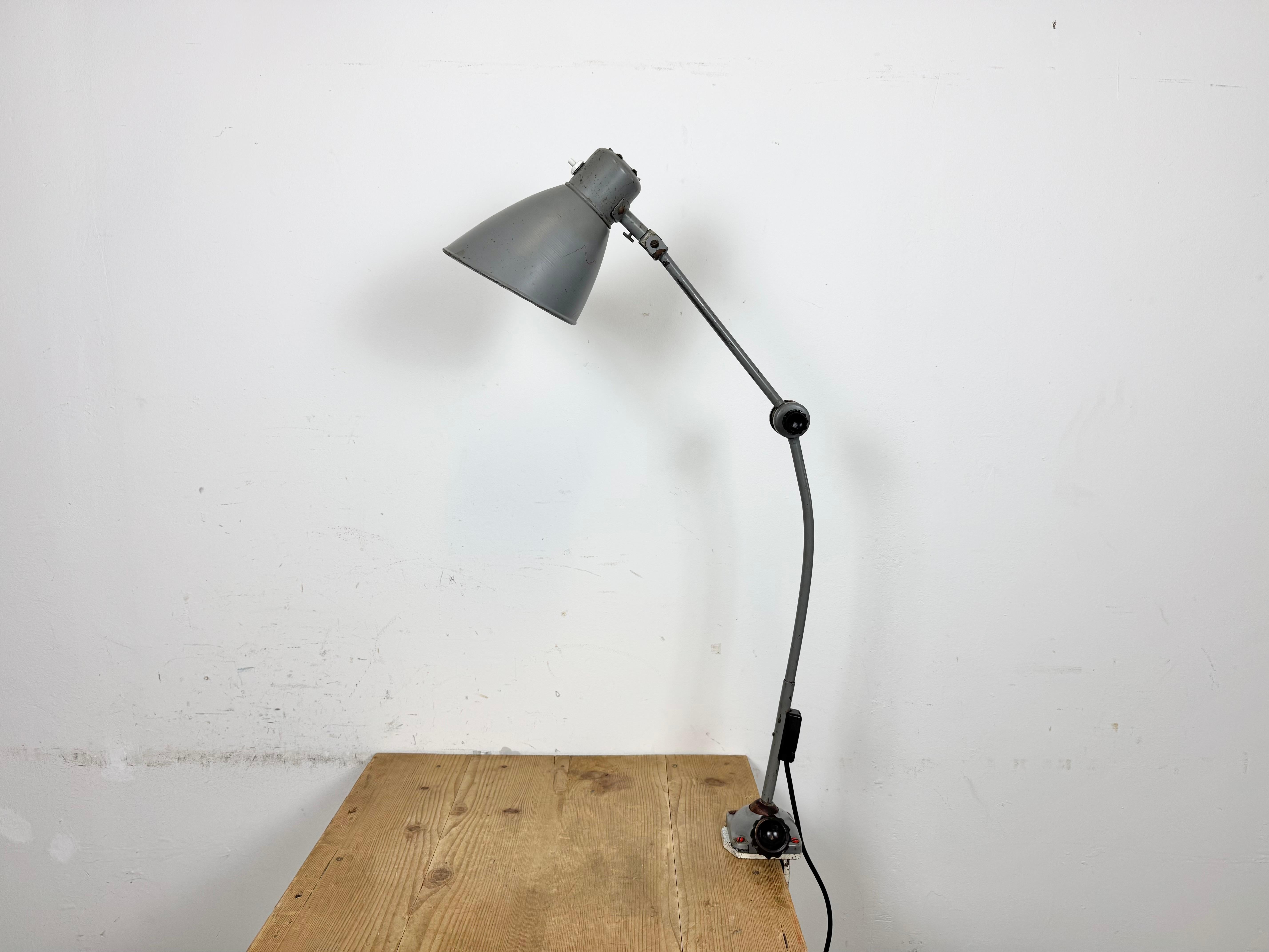 Large industrial table lamp with three adjustable joints made in former Czechoslovalia during the 1960s.It features a grey iron clamp base ,arm and lampshade. The original socket requires E 27/E 26 light bulbs. New wire. The diameter of the shade is