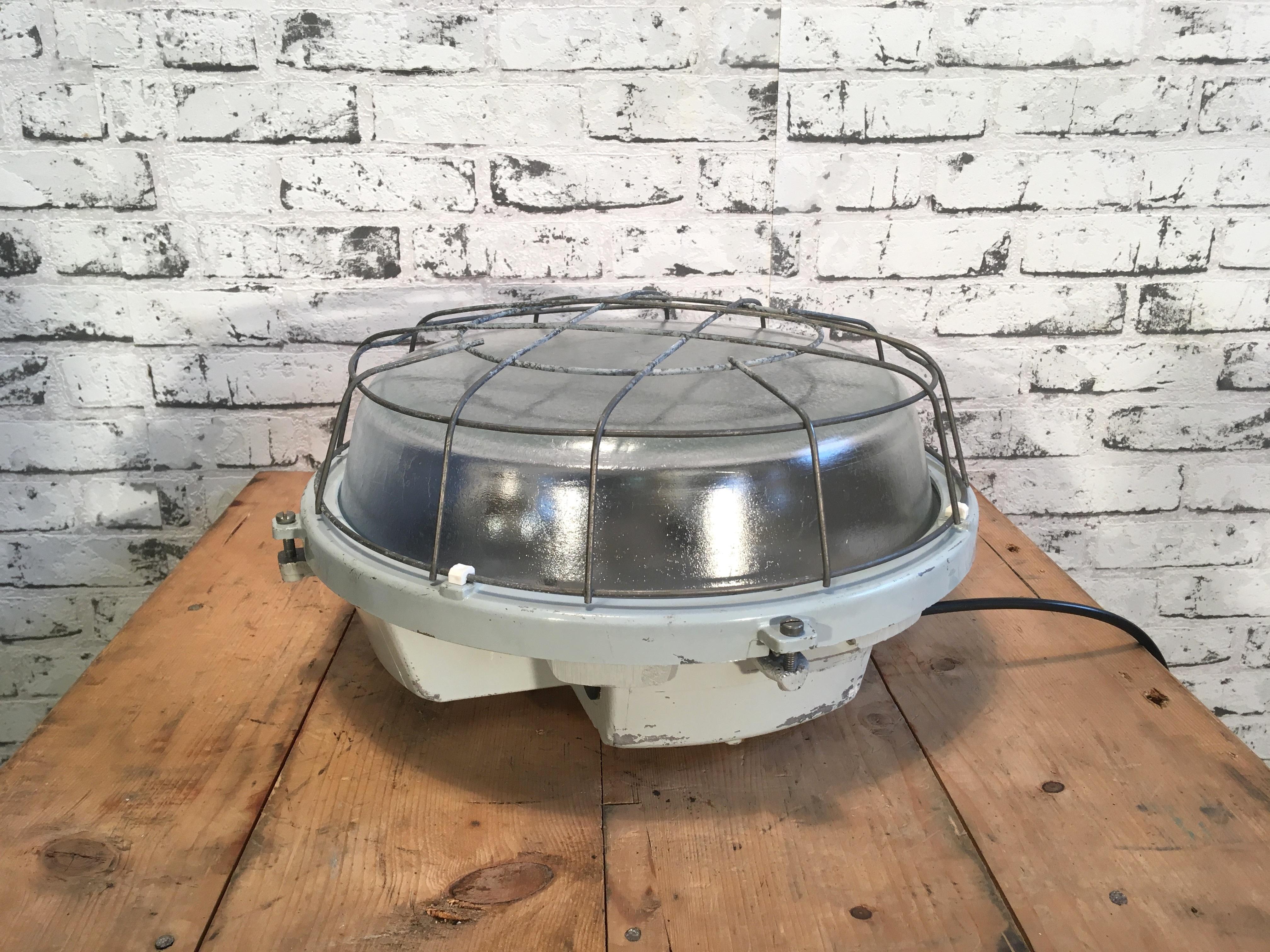 This grey cast aluminium wall lamp was made by Elektrosvit in former Czechoslovakia during the 1980s. It has two new porcelain E27 sockets, frosted curved glass cover and steel grid. It can also be used as a ceiling lamp. Weight of the lamp is 6.5