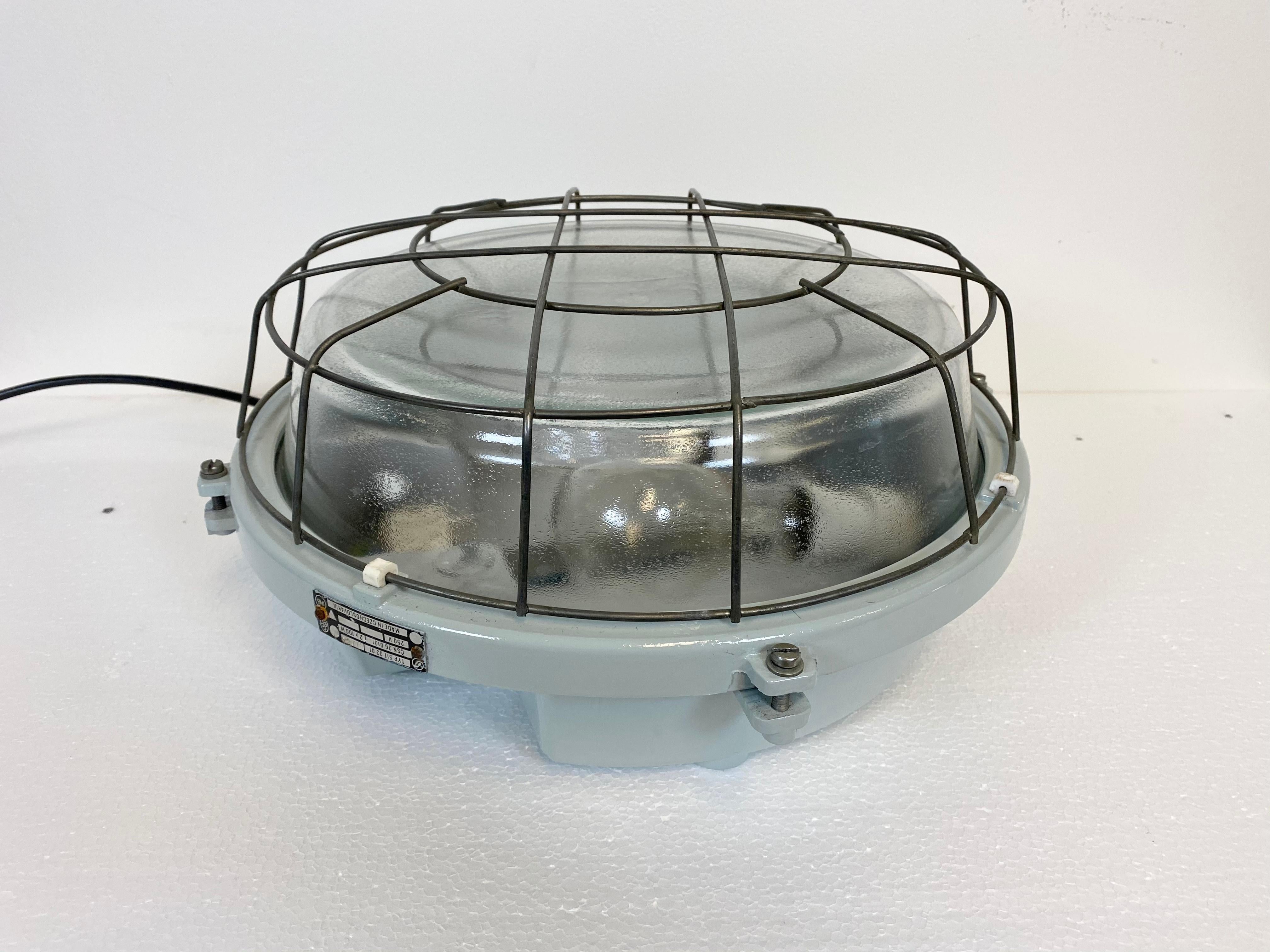 This grey wall lamp was made by Elektrosvit in former Czechoslovakia during the 1980s. It features cast aluminium body, frosted curved glass cover and steel grid. Two new porcelain sockets for E 27 lightbulbs and new wire. The light can also be used