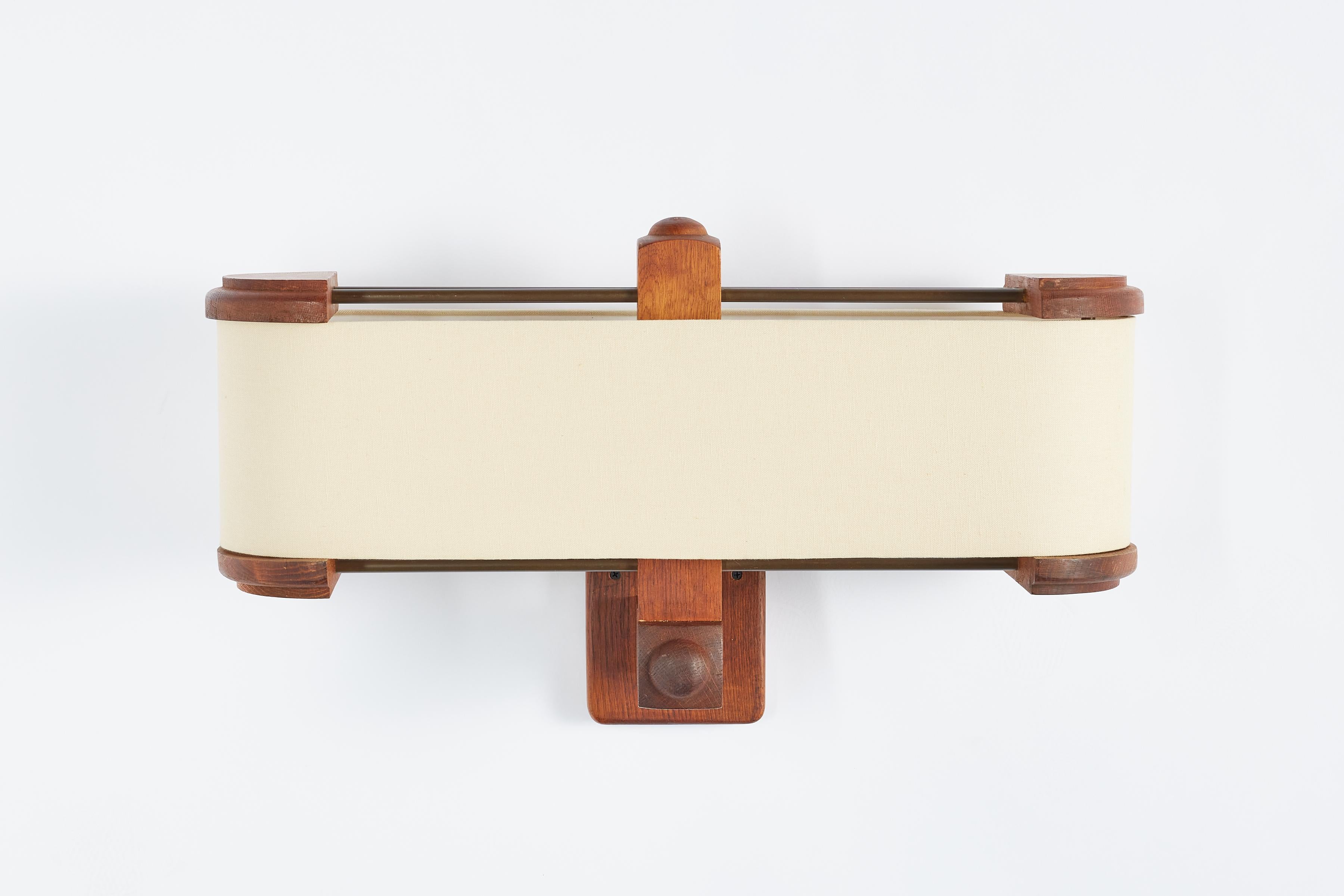 Rare wall sconce by Guillerme et Chambron extremely large in scale. 

Signature oak frame and new single linen shade with brass stretchers. 

France, 1940's

Newly rewired - 2 sockets
