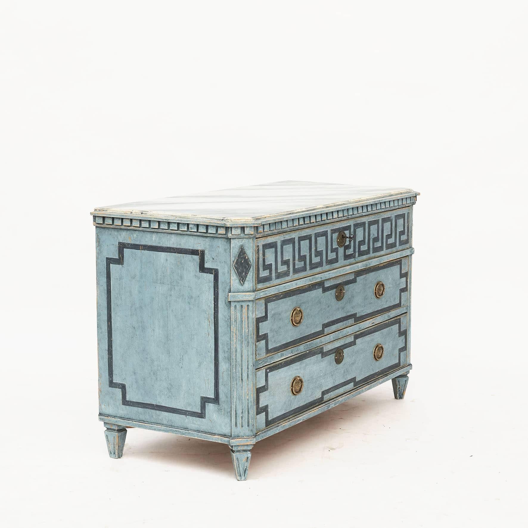 A decorative Swedish Gustavian style chest of drawers painted in blue shades. Wooden gray faux marbled tabletop.
Three drawer, upper drawer decorated with 
