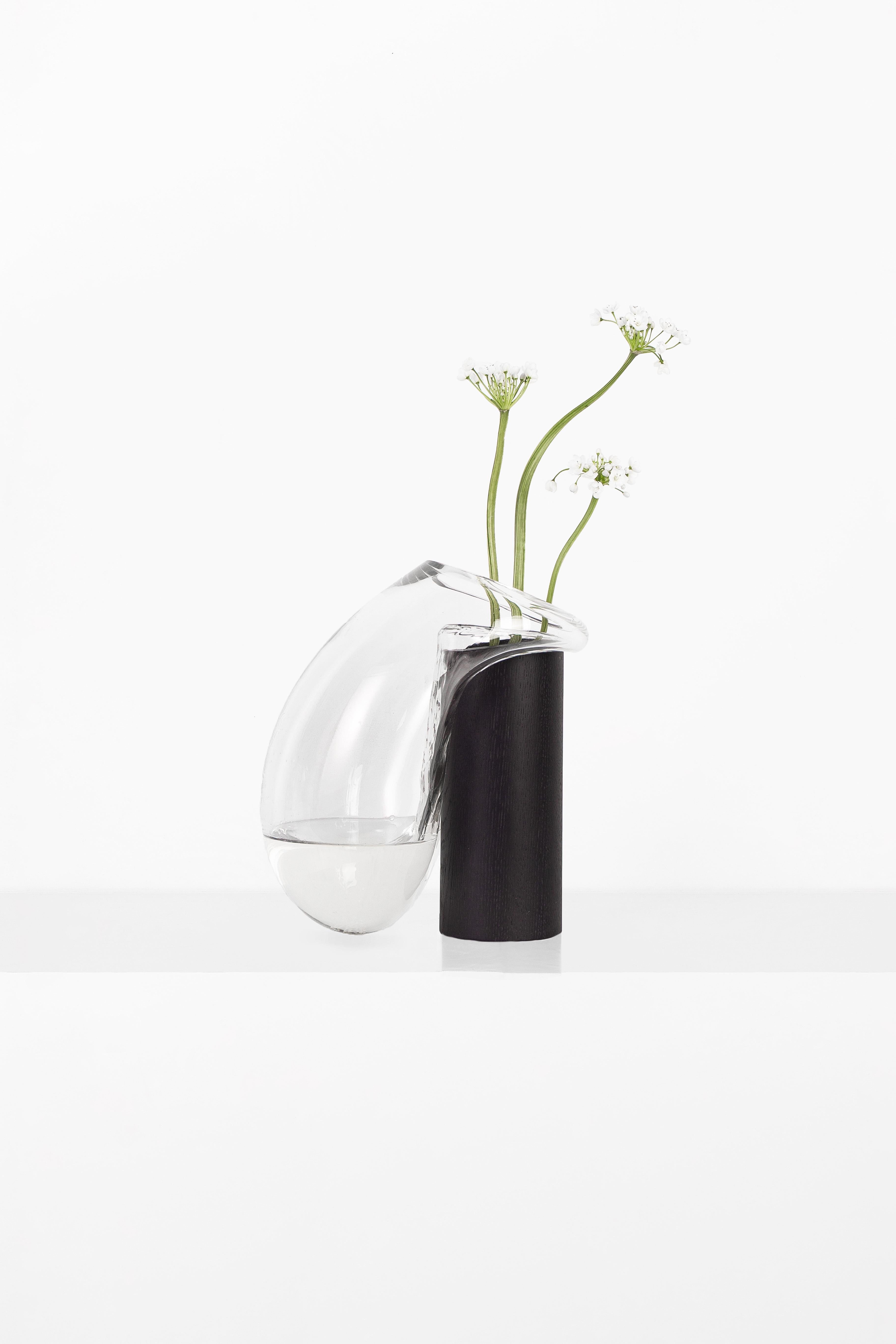 Vaso grande Gutta Boom CS1 di NOOM
Dimensioni: L. 20 x P. 21 x H. 30 cm 
Materiali: Vetro soffiato trasparente e Oak rivestito internamente con resina epossidica. 

I vasi scultorei in vetro 