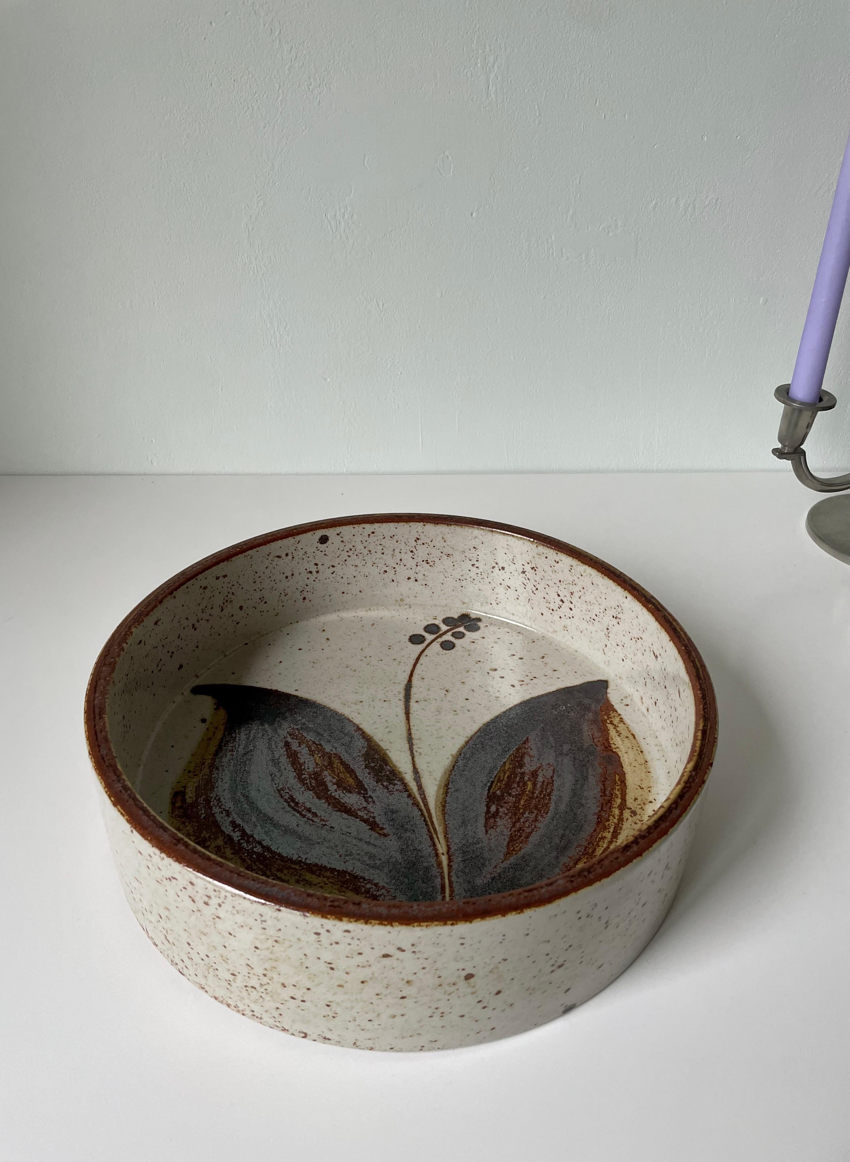 Large hand-thrown Scandinavian Modern stoneware centerpiece bowl in light gray glaze with large earth colored stylized floral decor with large leaves in the center. Simple lines with tall straight edges lined with a warm brown color. Made for Søholm