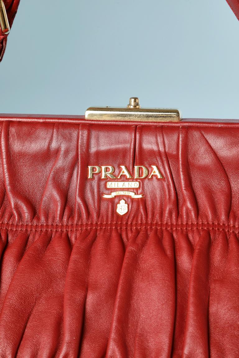 Large hand-bag in gathered red leather and gold metal details. Top-stitched. 
Key and lock. Branded nylon fabric lining. Pocket with zip inside. Gold metal studs underneath.
SIZE 40 cm X 35 cm (height) X 10 cm ( bottom width) 