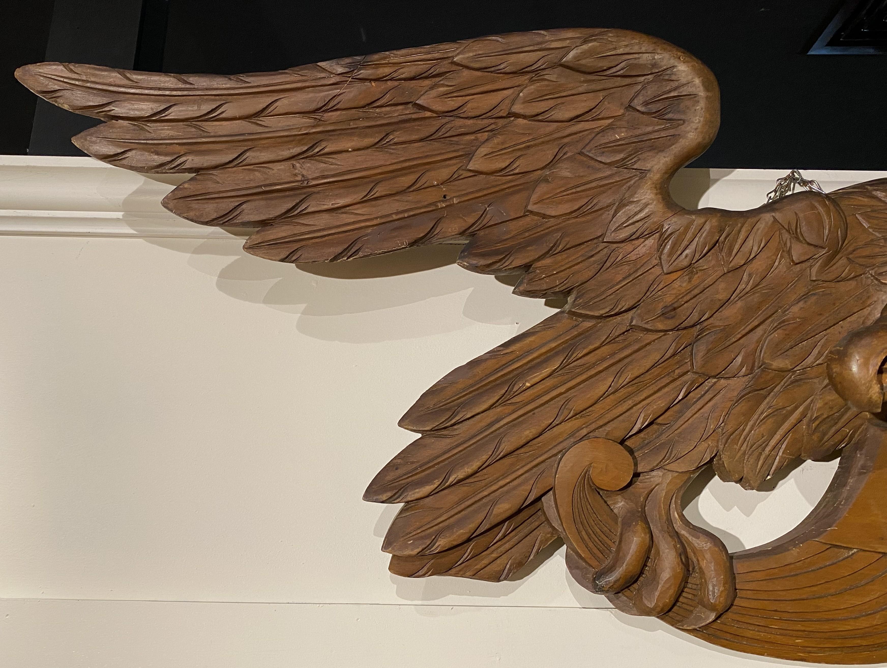 A large hand carved American eagle with spread wings and flag or shield, with fine detail and original finish, dating to the 20th century in very good condition, with minor imperfections and wear commensurate with age and use. A possible repair