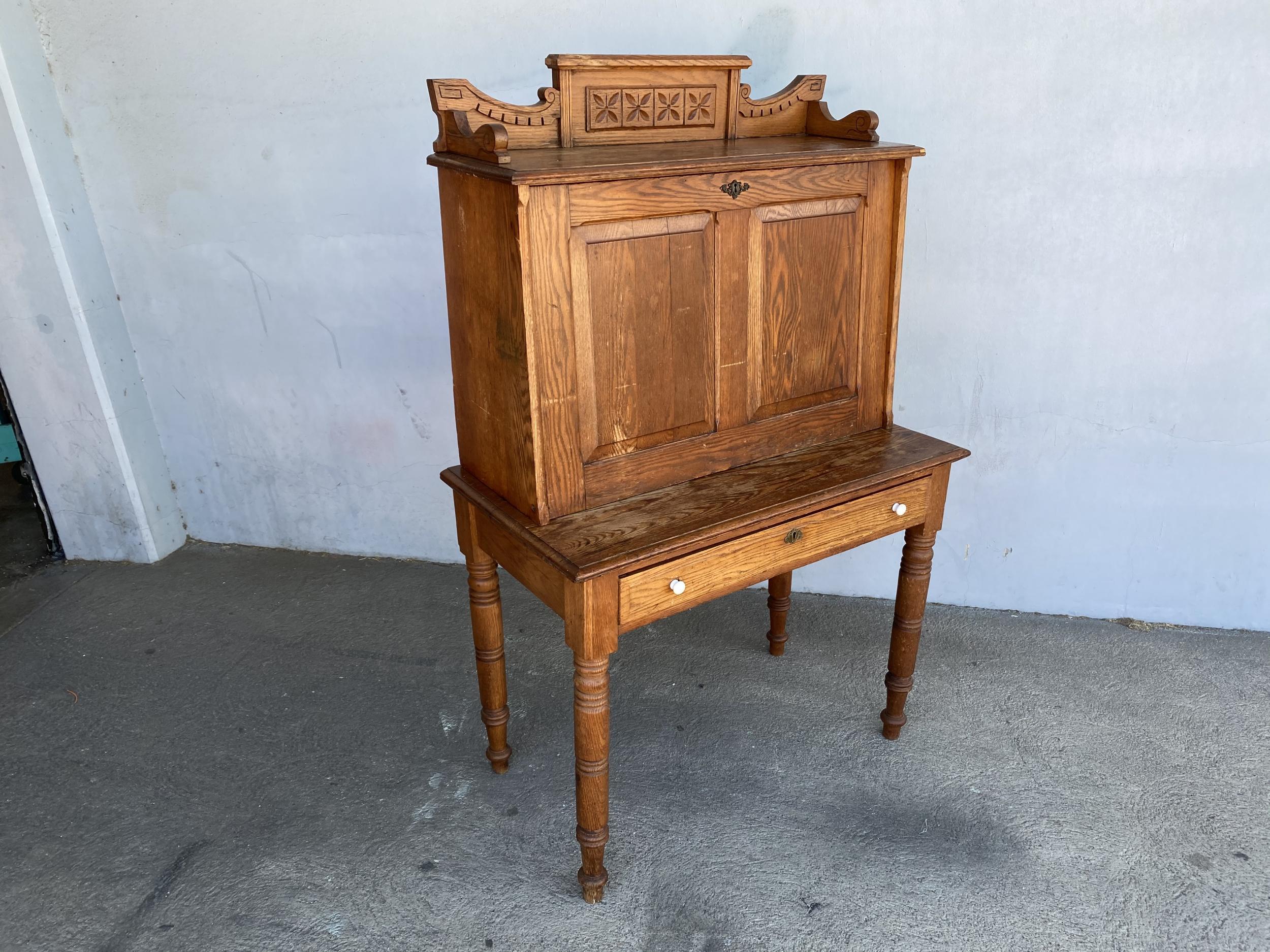Large hand carved antique Edwardian secretary desk featuring a folding down front with the front which opens to shelving and cubby spaces and one large drawer in the front.