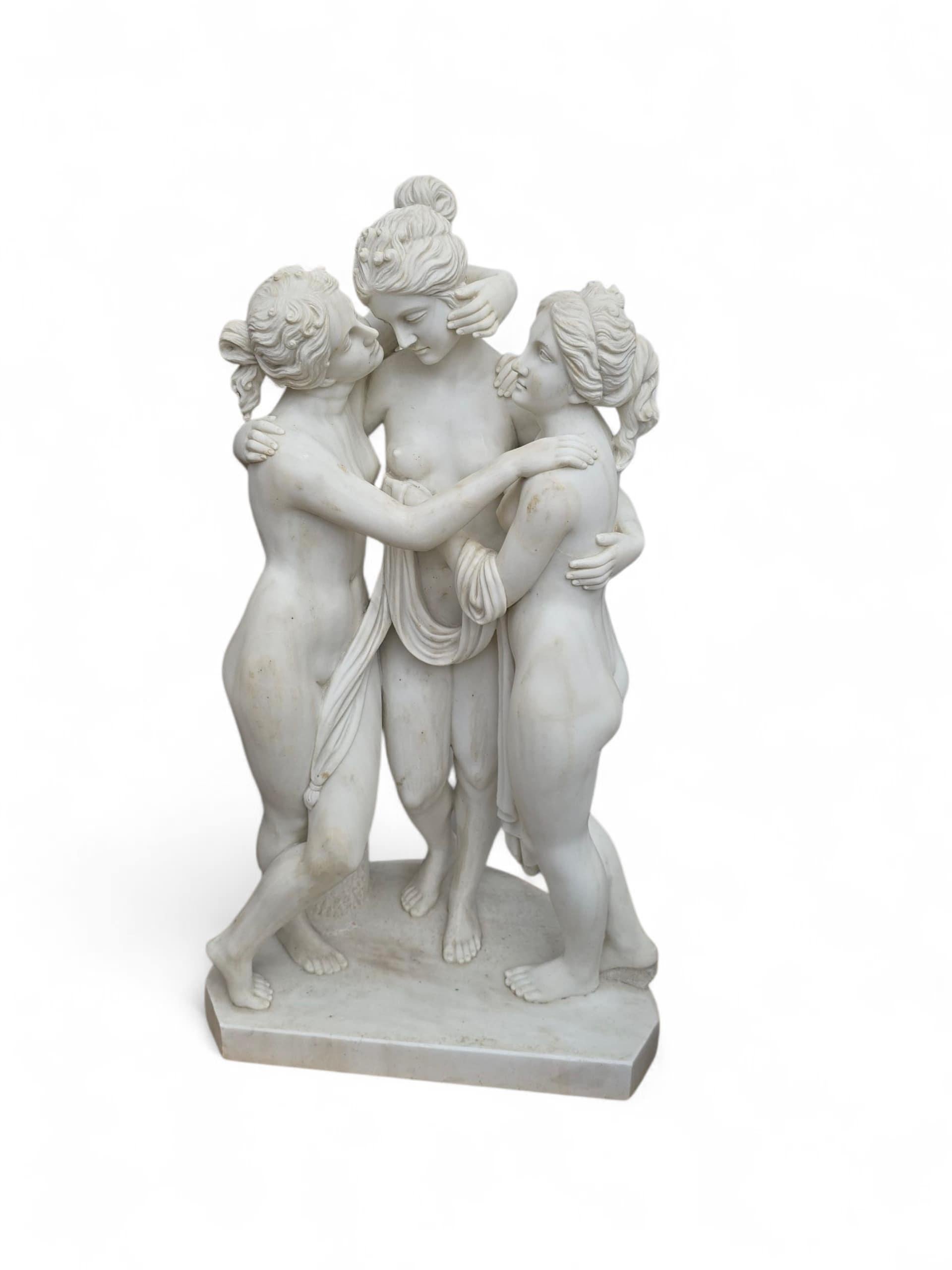 Elegante scultura in marmo finemente lavorata che raffigura Le Tre Grazie, scolpita a mano in marmo bianco di Carrara in Italia nel XX secolo. Il trio di figure femminili classiche, simbolo di bellezza, fascino e gioia, è raffigurato mentre si