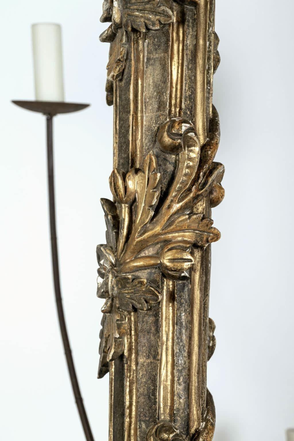Massiccio lampadario italiano a dodici bracci intagliato e dorato a mano, appena cablato. Ghirlanda in legno d'orato intagliata a mano intorno al corpo scanalato dorato e dipinto di grigio-verde. Restaurato con dodici bracci di ferro forgiati di