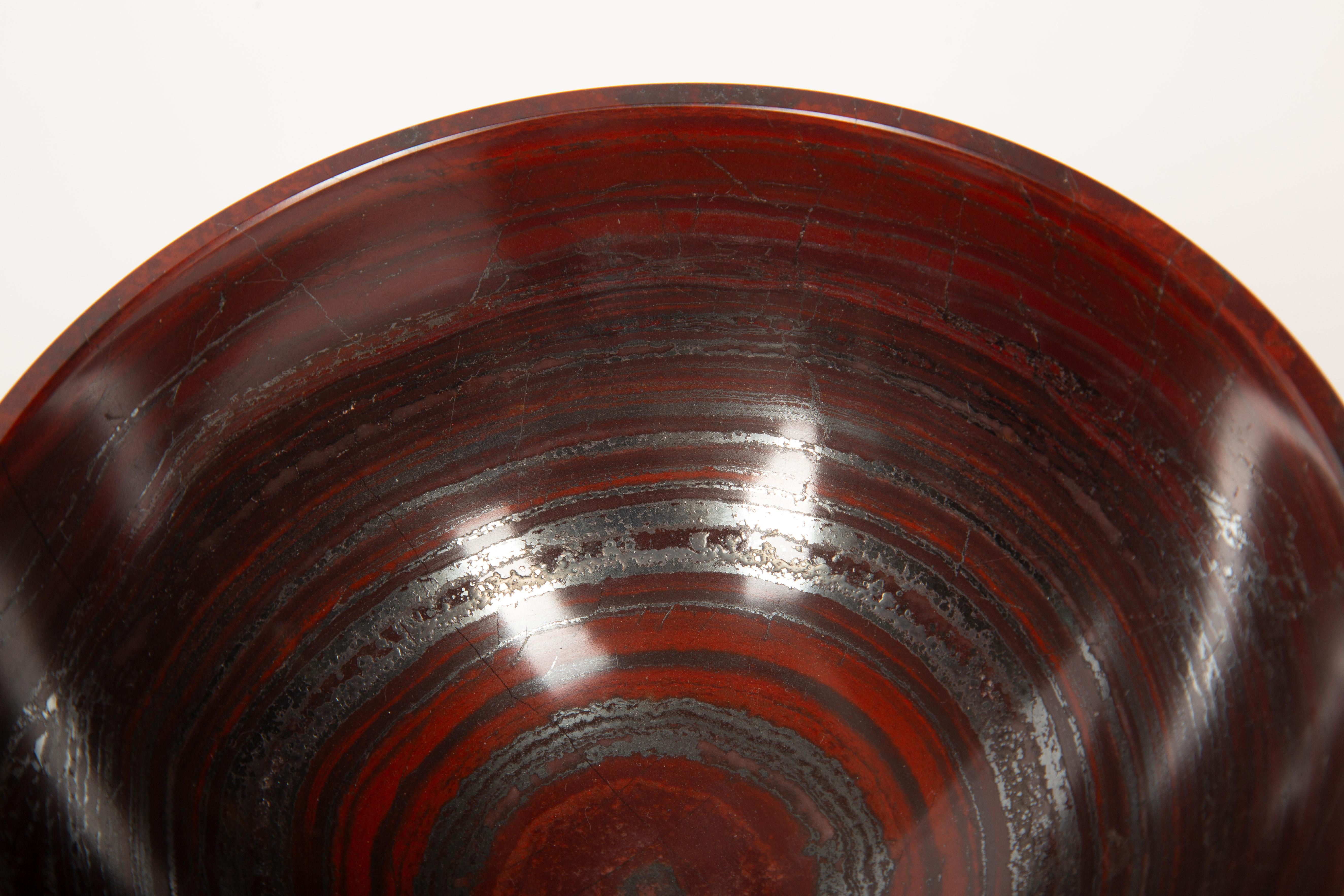Ce magnifique bol en pierre, sculpté et poli à la main, présente un motif naturel saisissant composé d'une alternance de bandes d'hématite (argent) et de jaspe (rouge), créant un contraste visuel envoûtant. Mesurant 6 pouces de diamètre, cette pièce