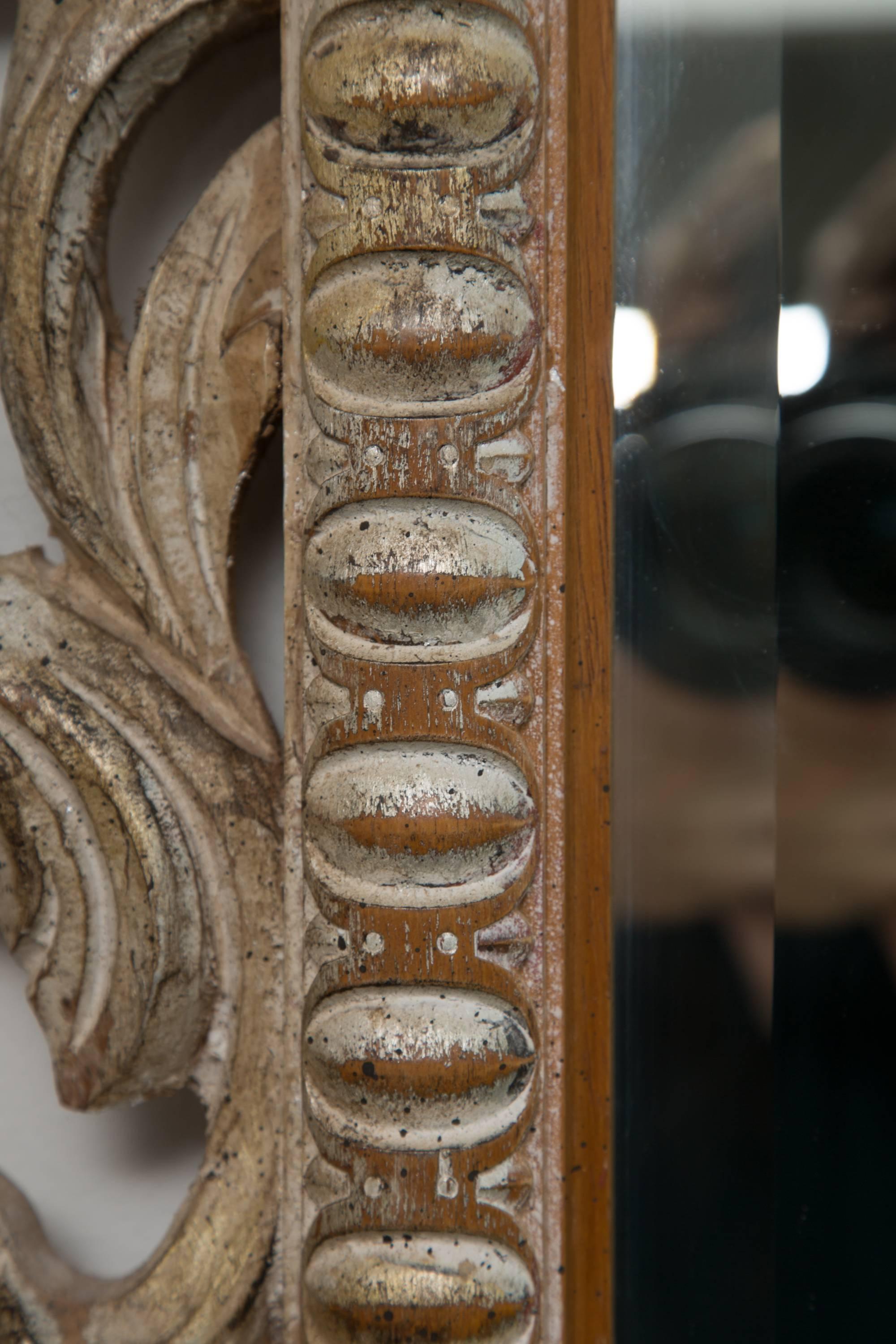 This wall mirror makes an incredible design for statement! The profusely hand carved frame in rococo fashion surrounds a beveled plate mirror. This 20th century wall mirror has a slight wash that gives the piece a pleasant patination.