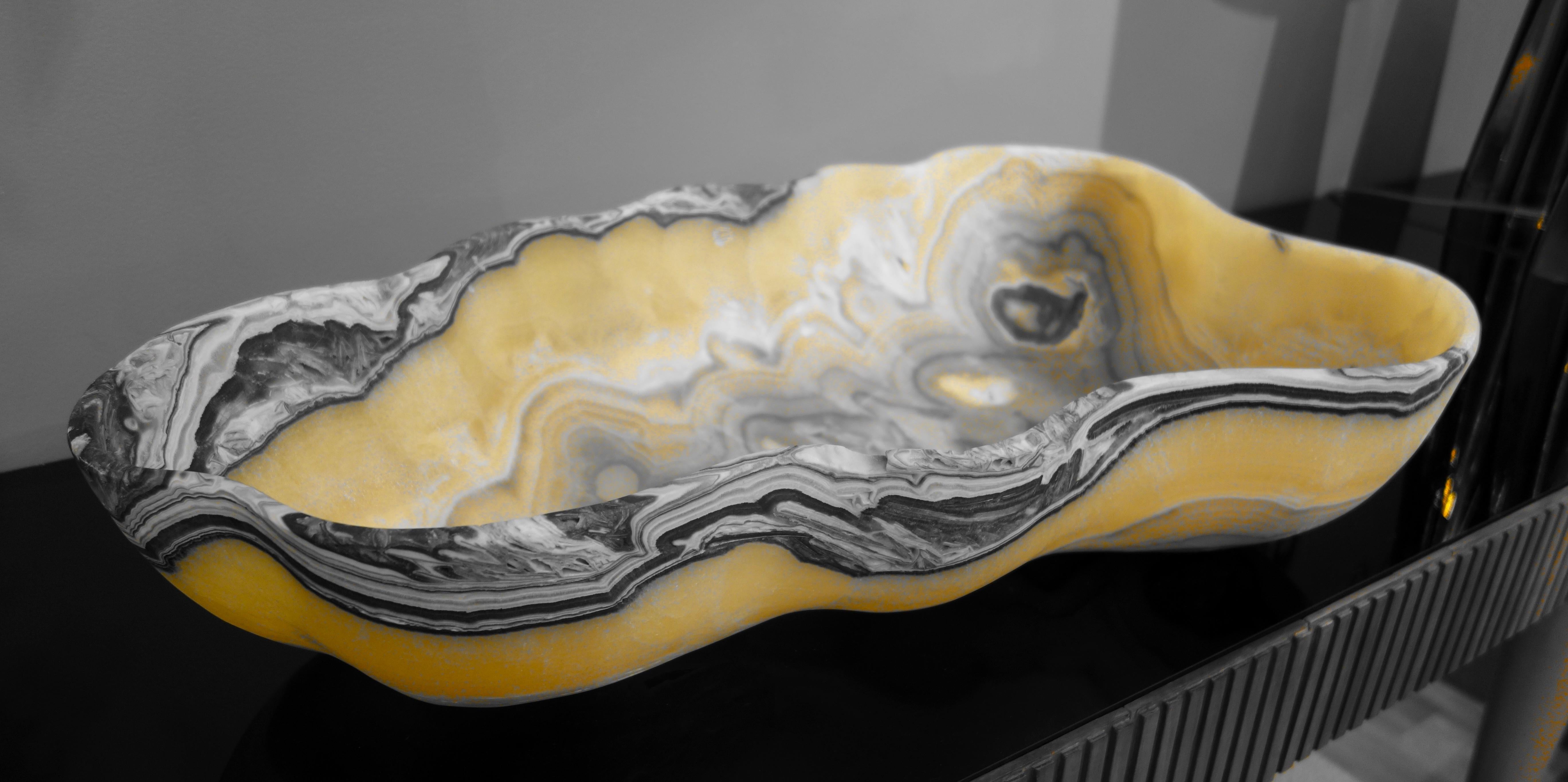 A very large hand carved Mexican onyx bowl or centerpiece in striking striations of gold, charcoal gray and white with natural negative spaces.