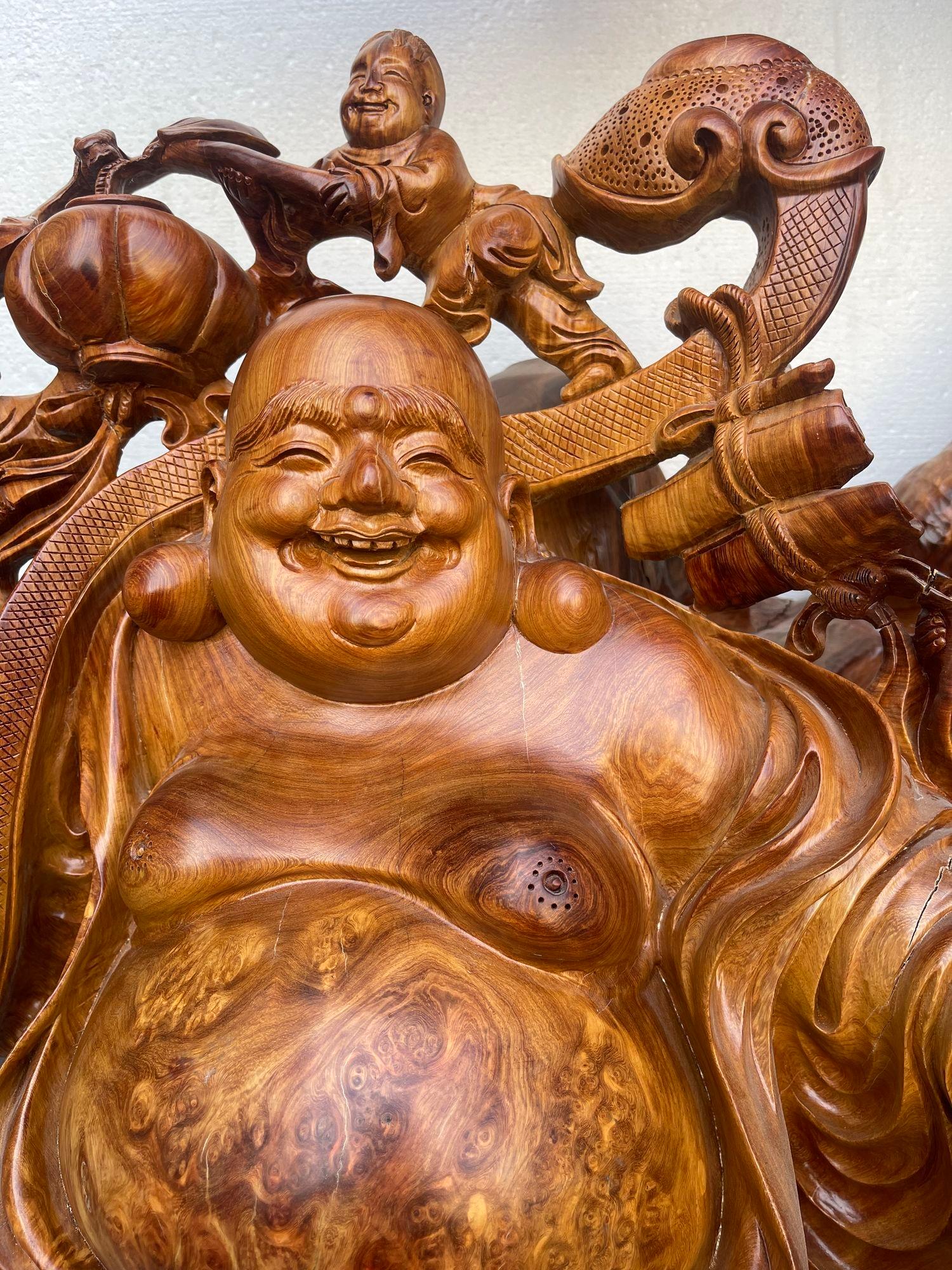 Senti il fascino e la positività di questo splendido Hotei Buddha intagliato a mano, realizzato in vibrante legno Padauk e radica. Questo incantevole pezzo raffigura il gioioso Hotei, noto anche come il Buddha che ride, accompagnato da bambini