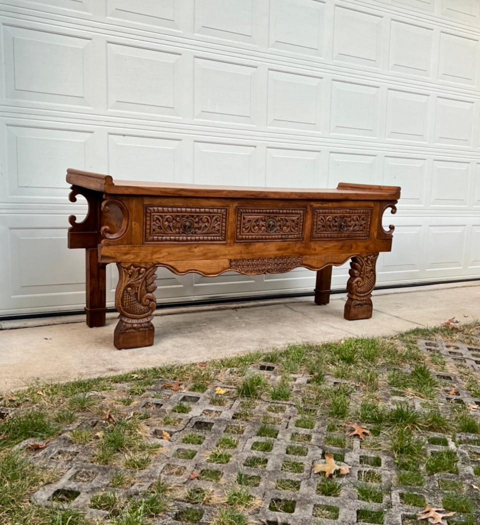 Very large hand-carved pine three drawer console table made in Indonesia, front of drawers and legs are heavily carved, table has and Asian flare similar to an altar table. It's very spectacular and would be and statement piece in any room.