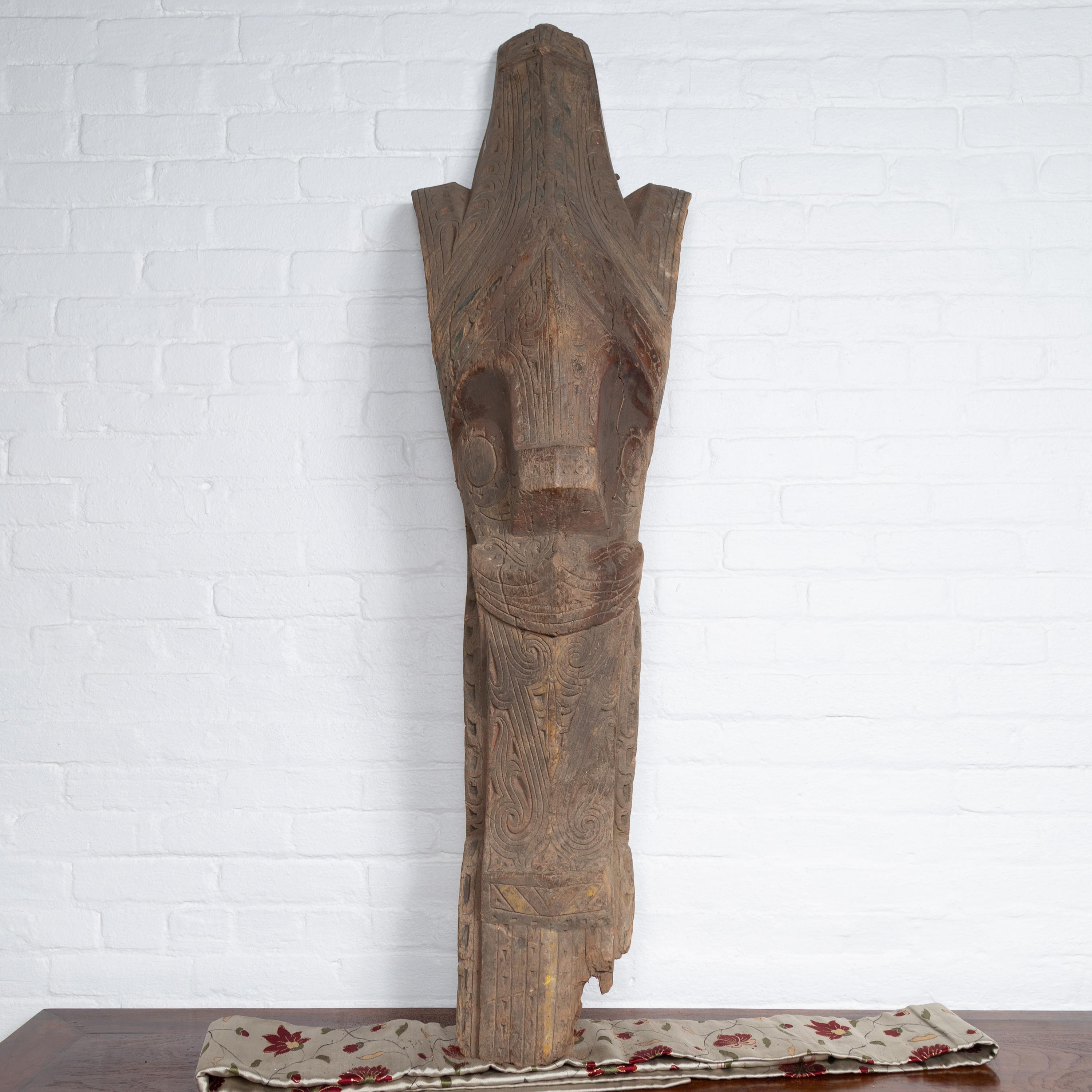 A large antique hand carved tribal carving from the Batak People, northern Sumatra, called a Singa Singa with traces of green and yellow polychromy and nicely weathered appearance. Attracting our eyes with its charismatic presence, this large hand