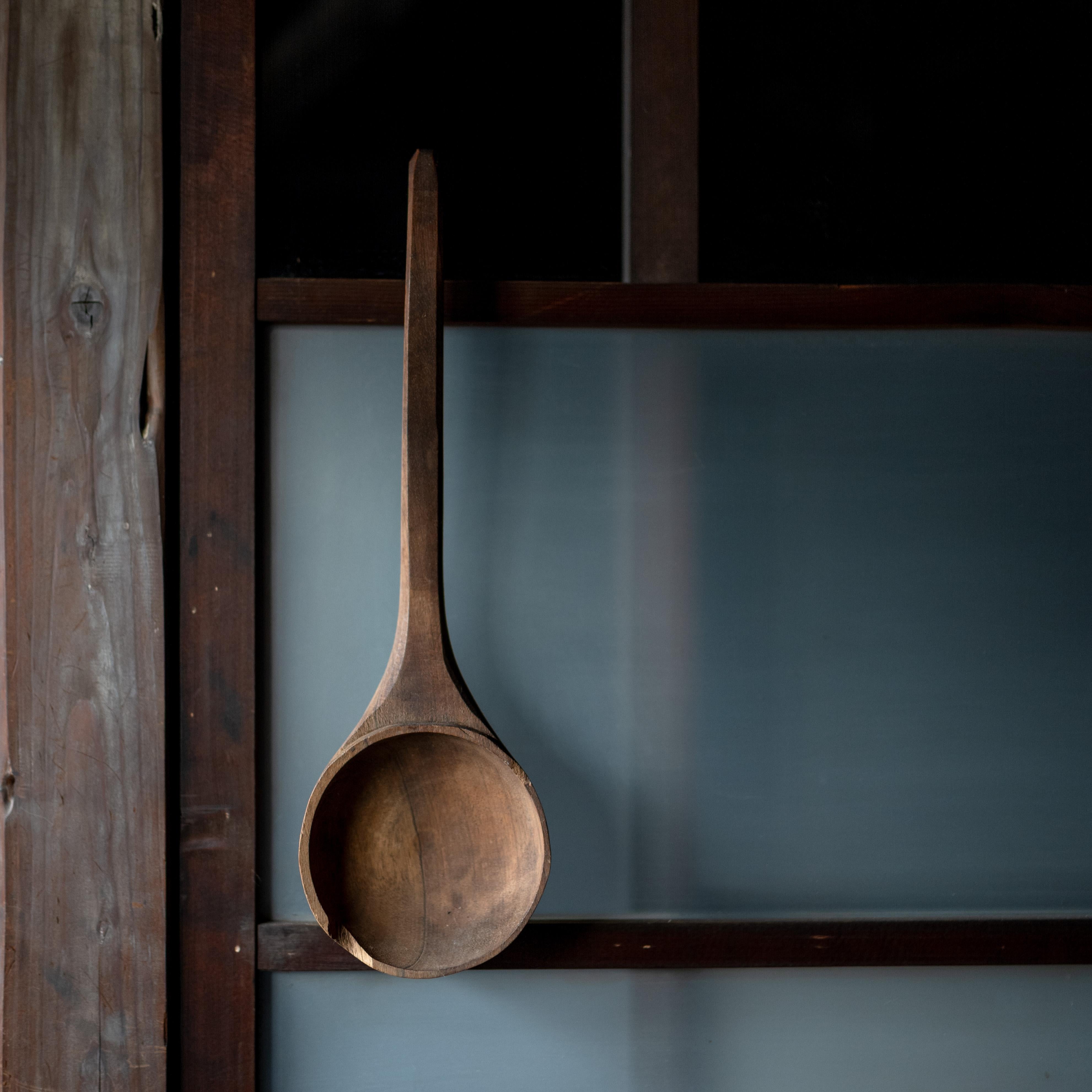Este cucharón grande de madera tallada a mano tiene un mango largo y elegante y un cuenco profundo y redondeado. Probablemente se utiliza para servir arroz o sopa en una cocina tradicional, y tiene una serena estética wabi-sabi que combina la