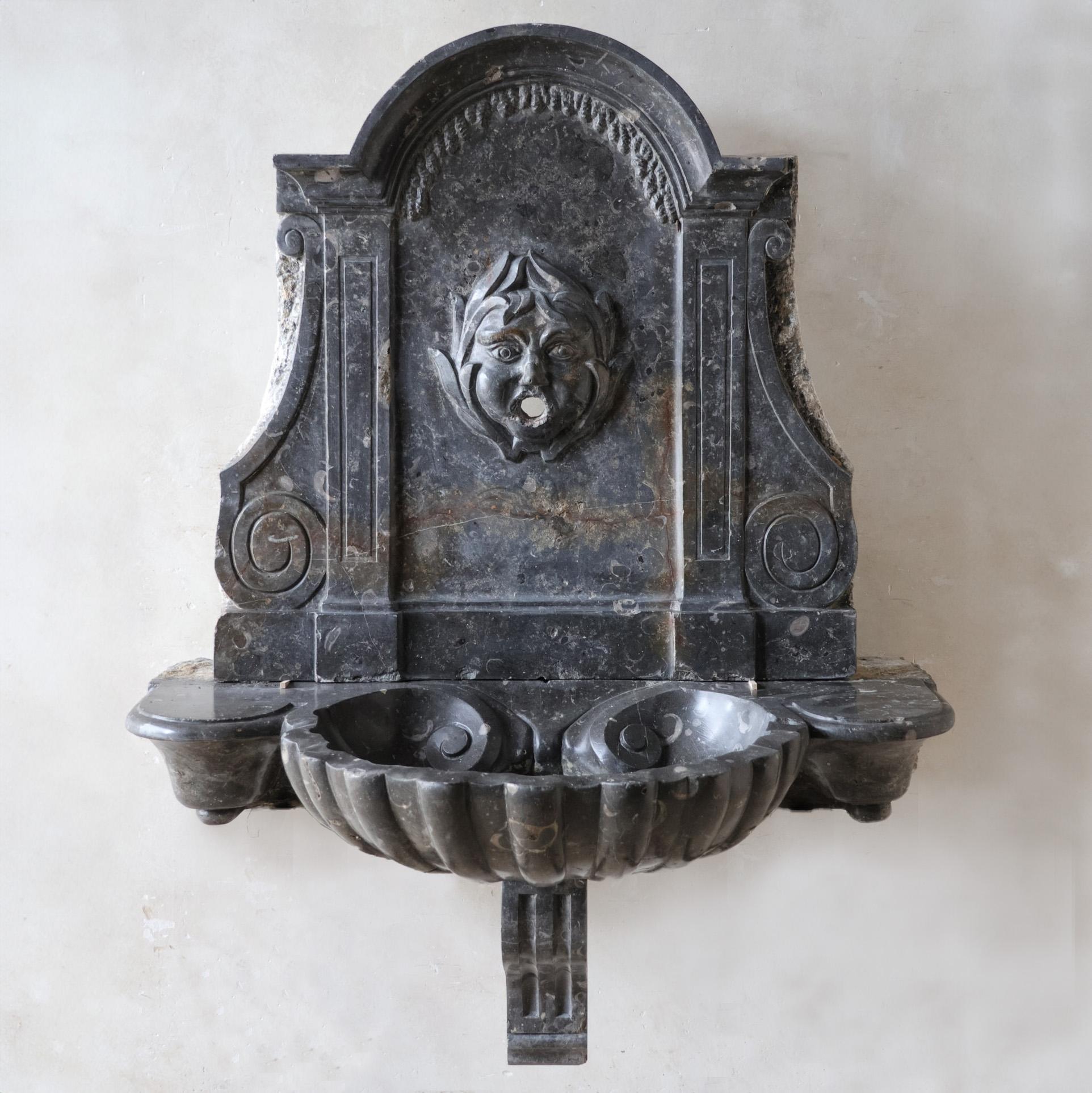 Exquisite, rare, hand-hewn St. Cyr marble wall fountain from the 18th century. This remarkable piece features a spout intricately crafted in the shape of a river god, cascading water into a large, shell-shaped bowl. The timeless elegance and