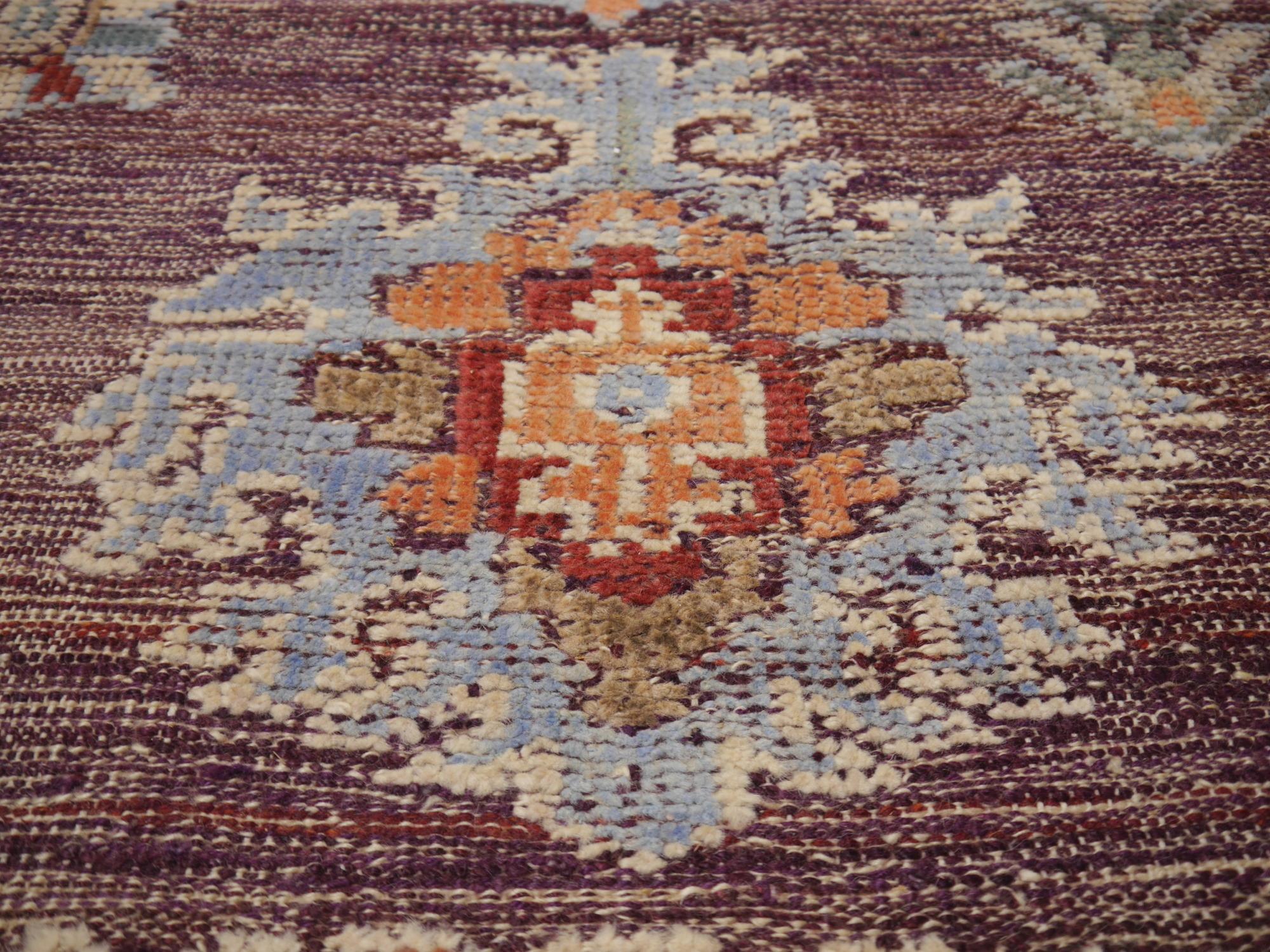 A large room sized rug with design in style of Oushak.
This beautiful rug was handmade using two different styles. The background is flat-woven Kilim and the motives are hand knotted. This results a special rustic look. The purple color is