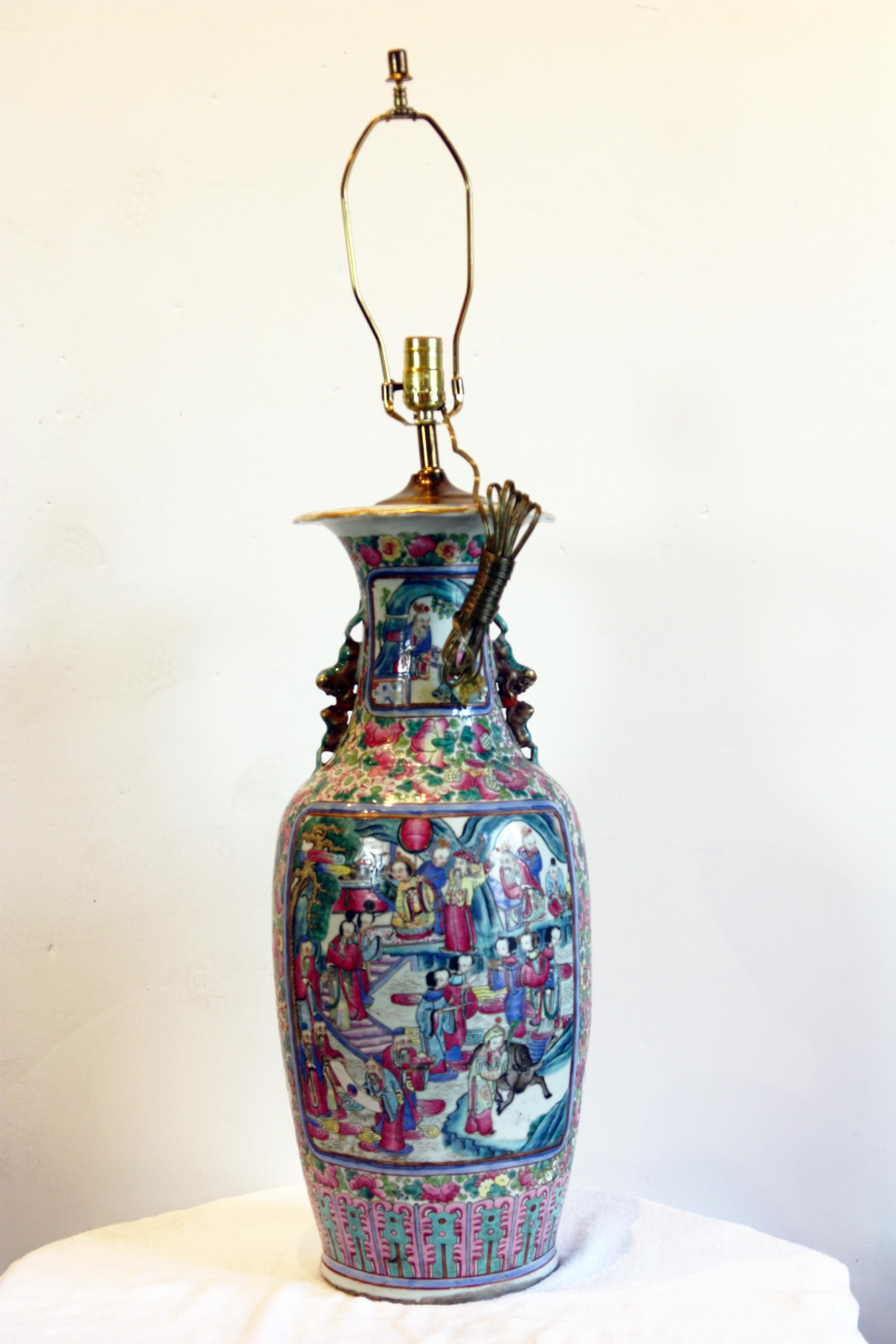 Large, beautifully hand-painted vase lamp. Royal scenes, foo dogs, gardens and flowers adorn the piece. Cat handles on the neck of the vase. Shade not included.