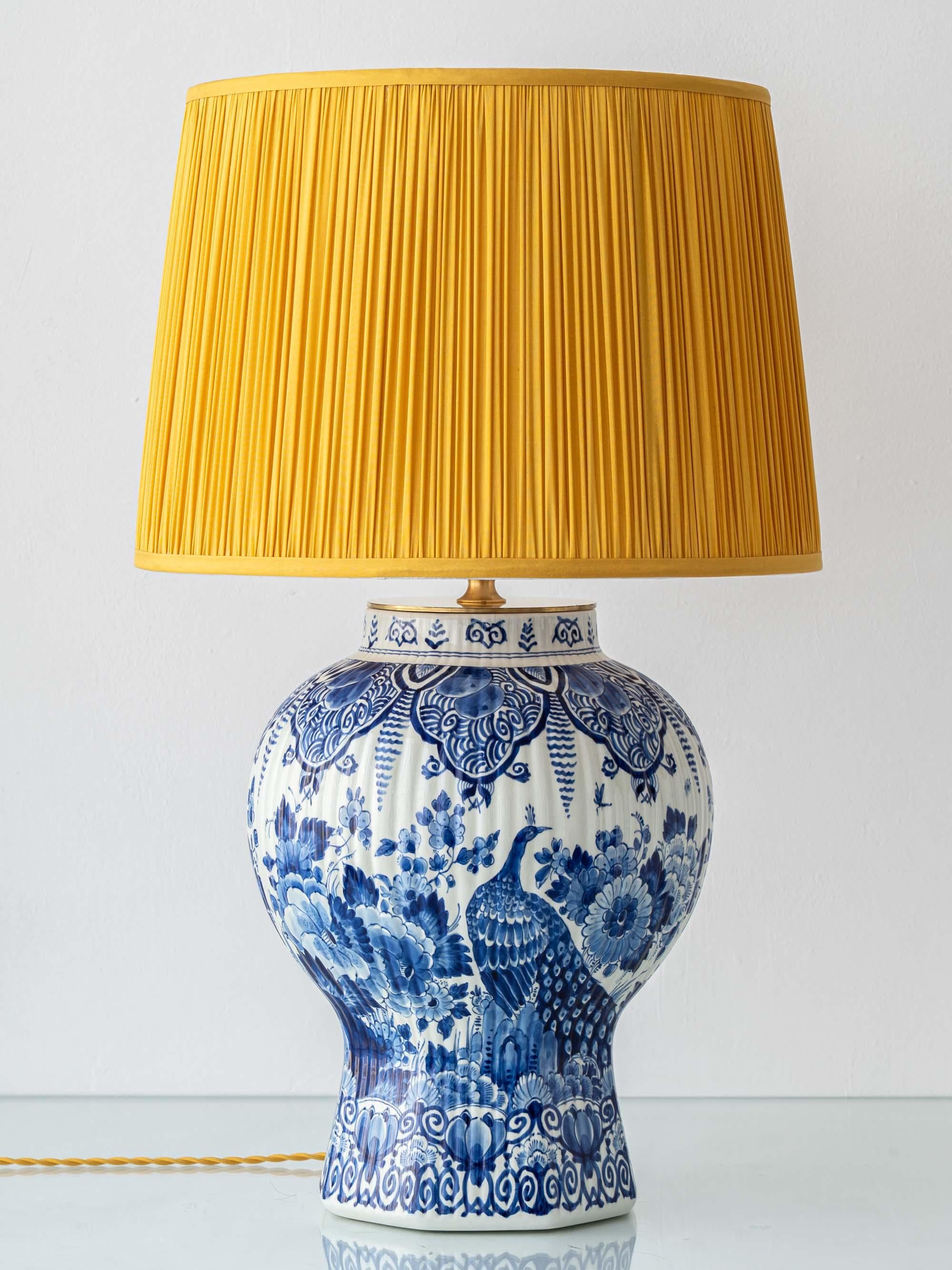 Large 1961 Royal Delft vase lamp with peacock motif, hand-painted in Delft Blue, paired with a mustard silk pleated lampshade by Amitābha Studio.

Meticulously handcrafted by Amitābha Studio from a large vintage 1961 Royal Delft (De Porceleyne Fles)