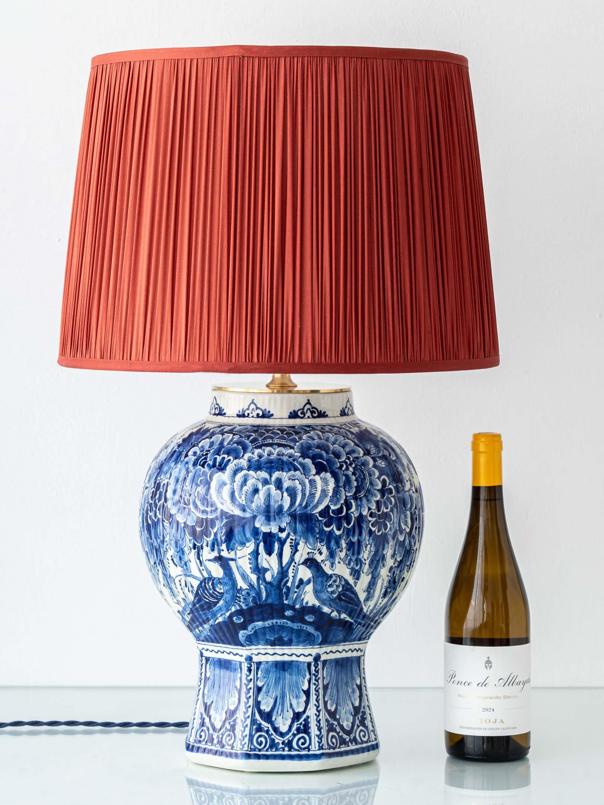 Une grande lampe de table en c�éramique bleue et blanche, unique en son genre, fabriquée à la main par le Studio Amitābha à partir d'un vase Royal Delft de 1948, associée à un abat-jour plissé en soie safran et à des accessoires en laiton.

Royal