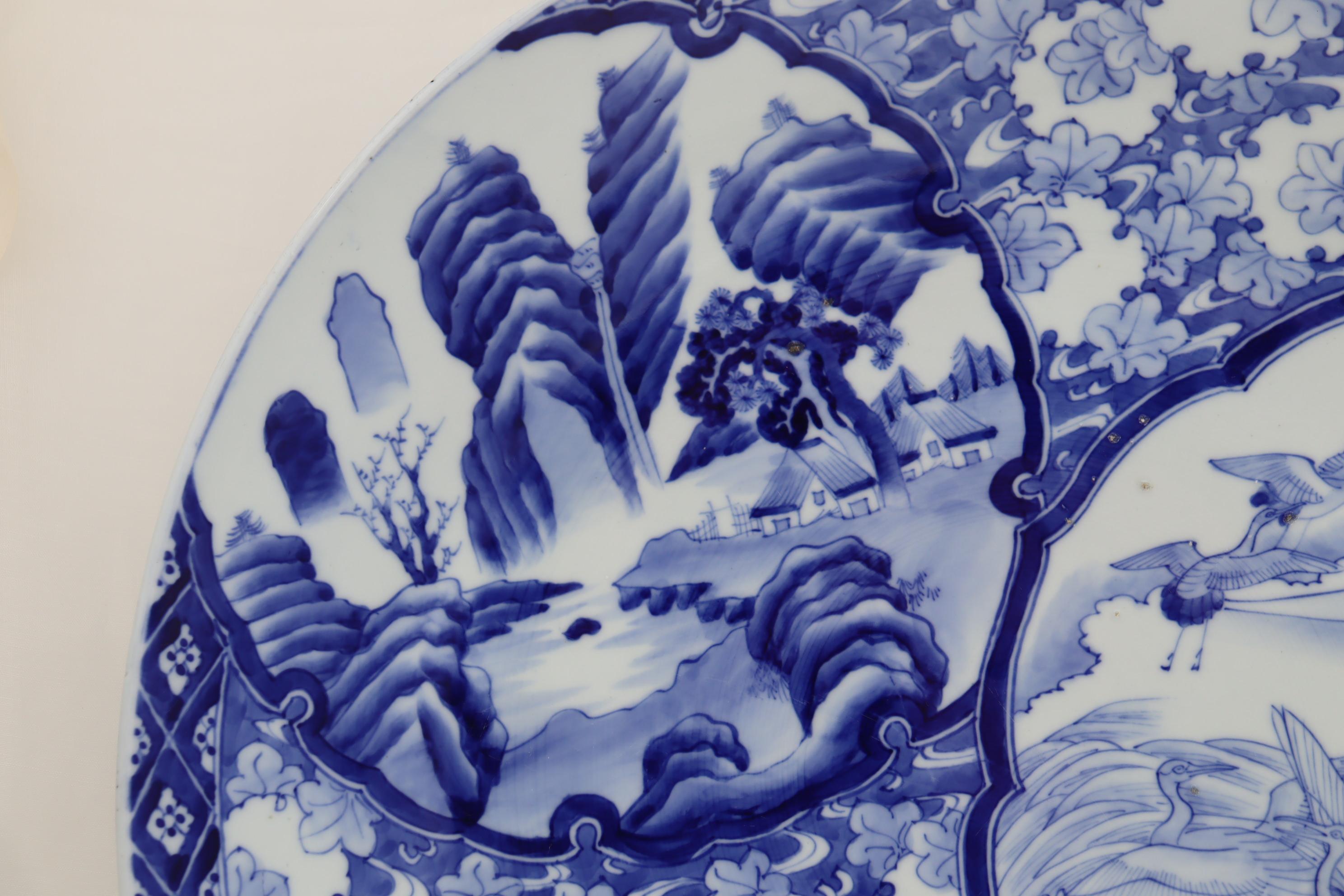 This very large Japanese hand painted blue and white charger is a testament to the skills of its potter, because to throw and successfully fire such a large item is rather unusual. It has a diameter of 540 mm (21.25 inches), stands 78 mm (3 inches)