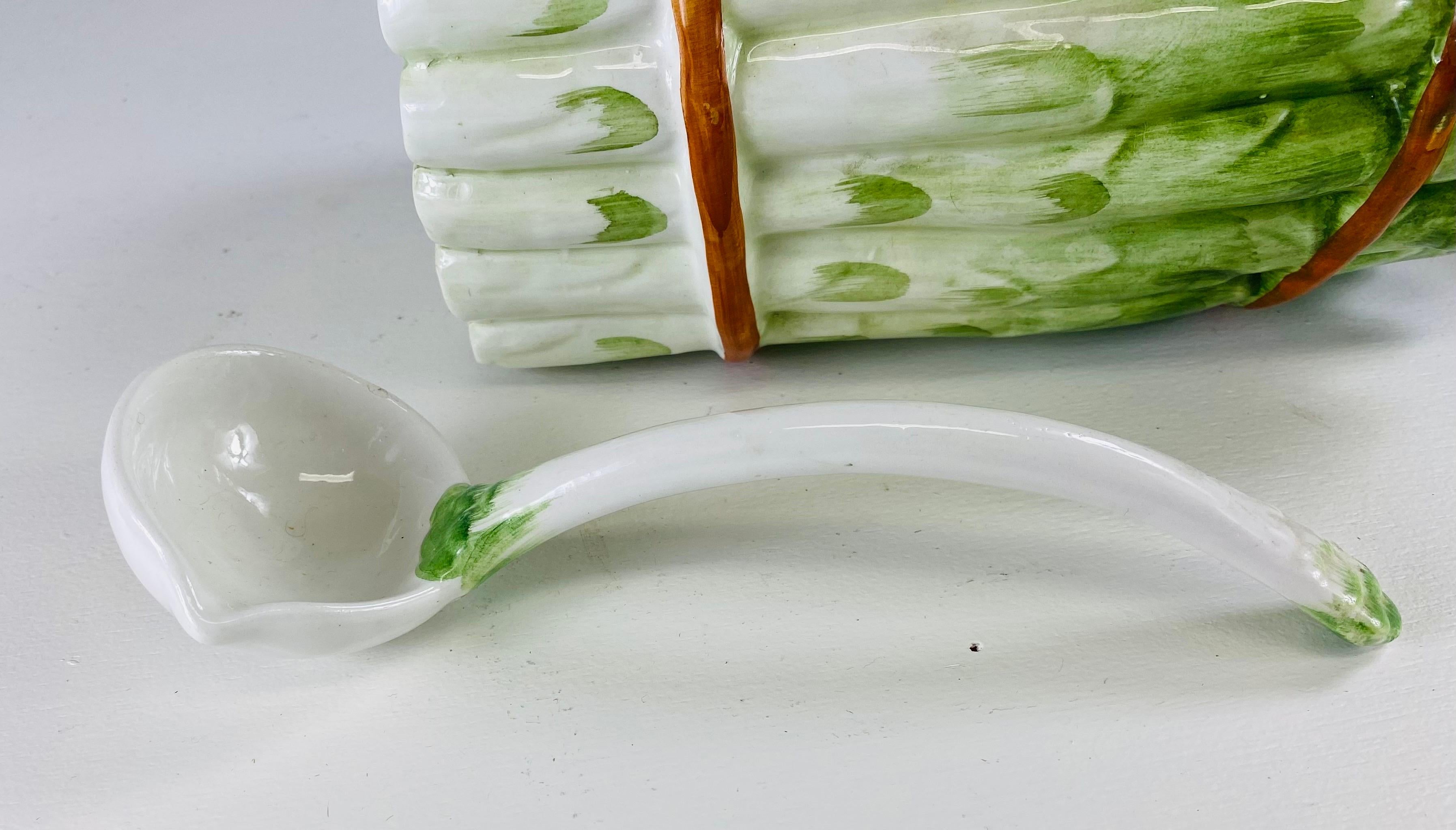 Dies ist eine große handbemalte Porzellan-Spargel-Terrine. Diese Terrine aus Porzellan ist einem Spargelbündel nachempfunden. Die Terrine wurde von Hand in tiefen Grün-, Creme- und Brauntönen glasiert. Die Terrena hat ihre originale Schöpfkelle und