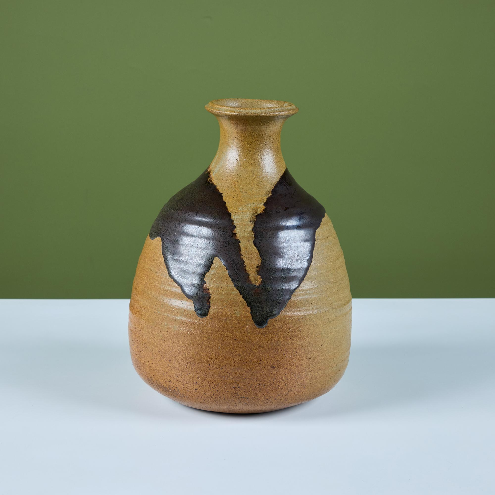 Vaso in Studio Pottery con smalto variegato verde oliva e marrone. Il vaso ha un corpo affusolato con una bocca a tulipano. La base del vaso è di colore marrone maculato, mentre lo smalto verde oliva è stato applicato in modo irregolare e 