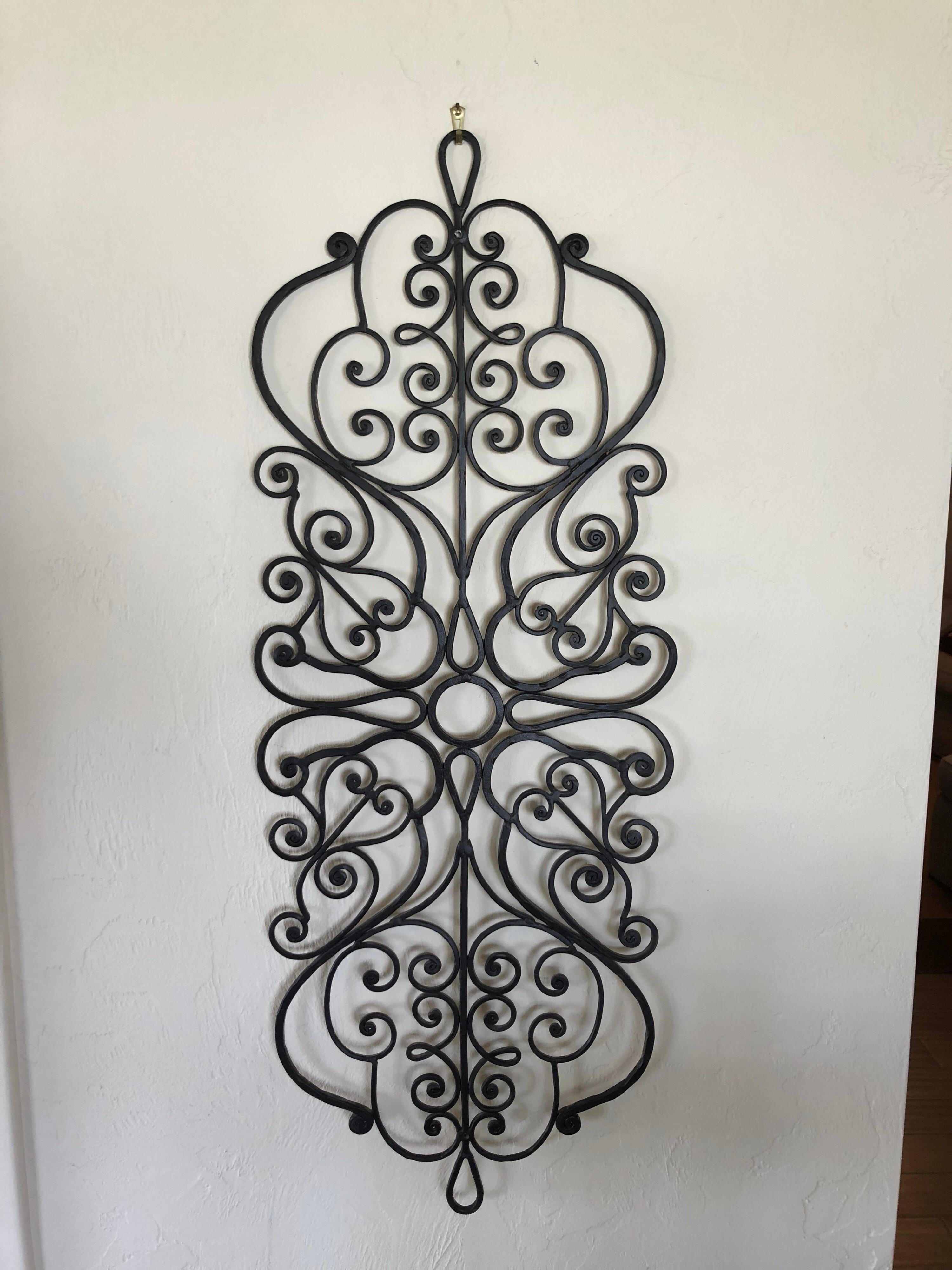 Large hand-wrought Iron wall sculpture. Ornate scrolls make up this decorative wall piece. This item is reversible or two sided. One side is a dark brown or black and the other is a light mustard golden yellow. This would look great on an exterior
