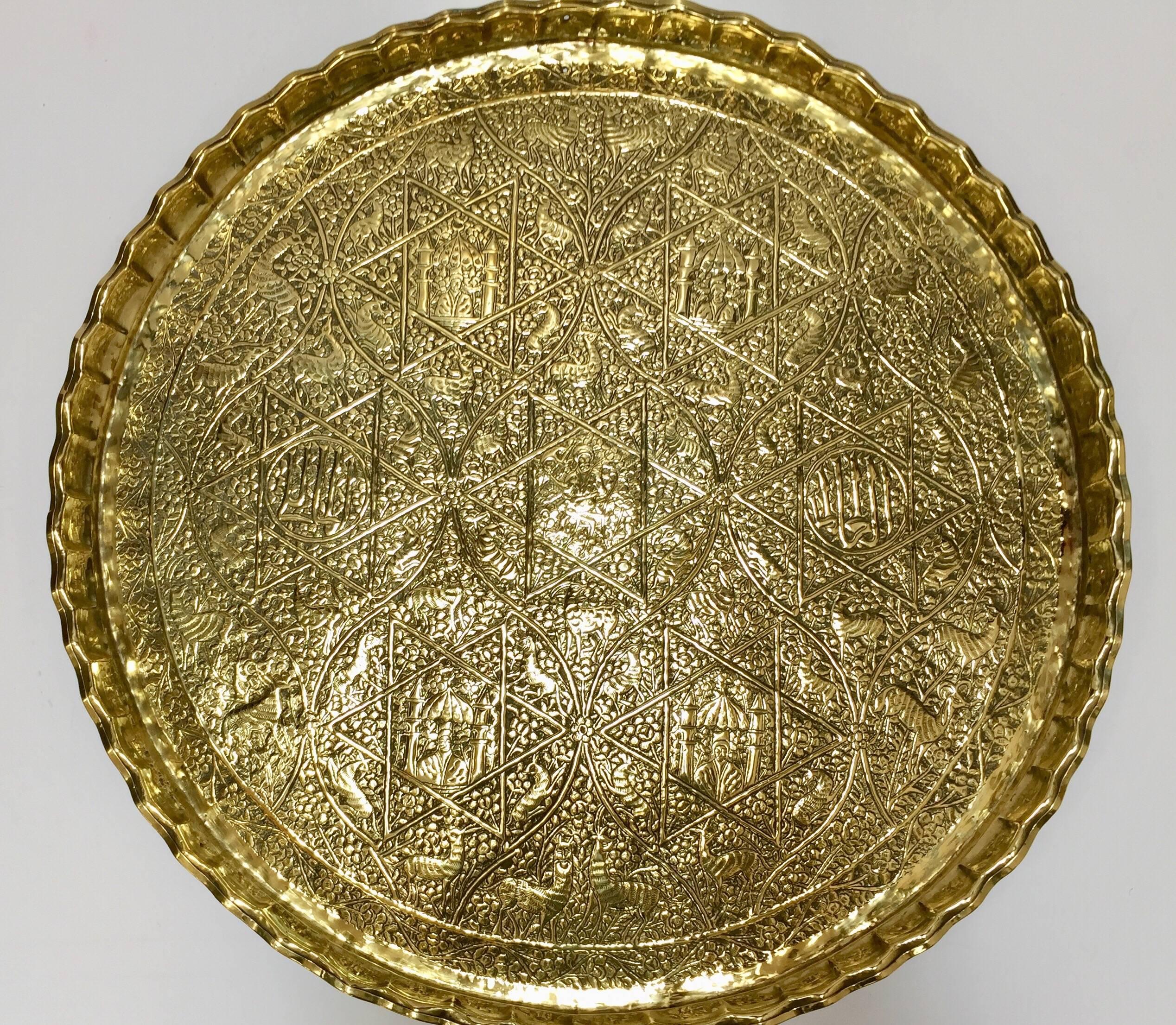 Large handcrafted decorative Indo-Persian brass tray.
Embossed and hammered with floral and figural and animals mystique scenes and Arabic calligraphy repousse writing in medallions.
Large decorative platter with pie crust edges.
Great for