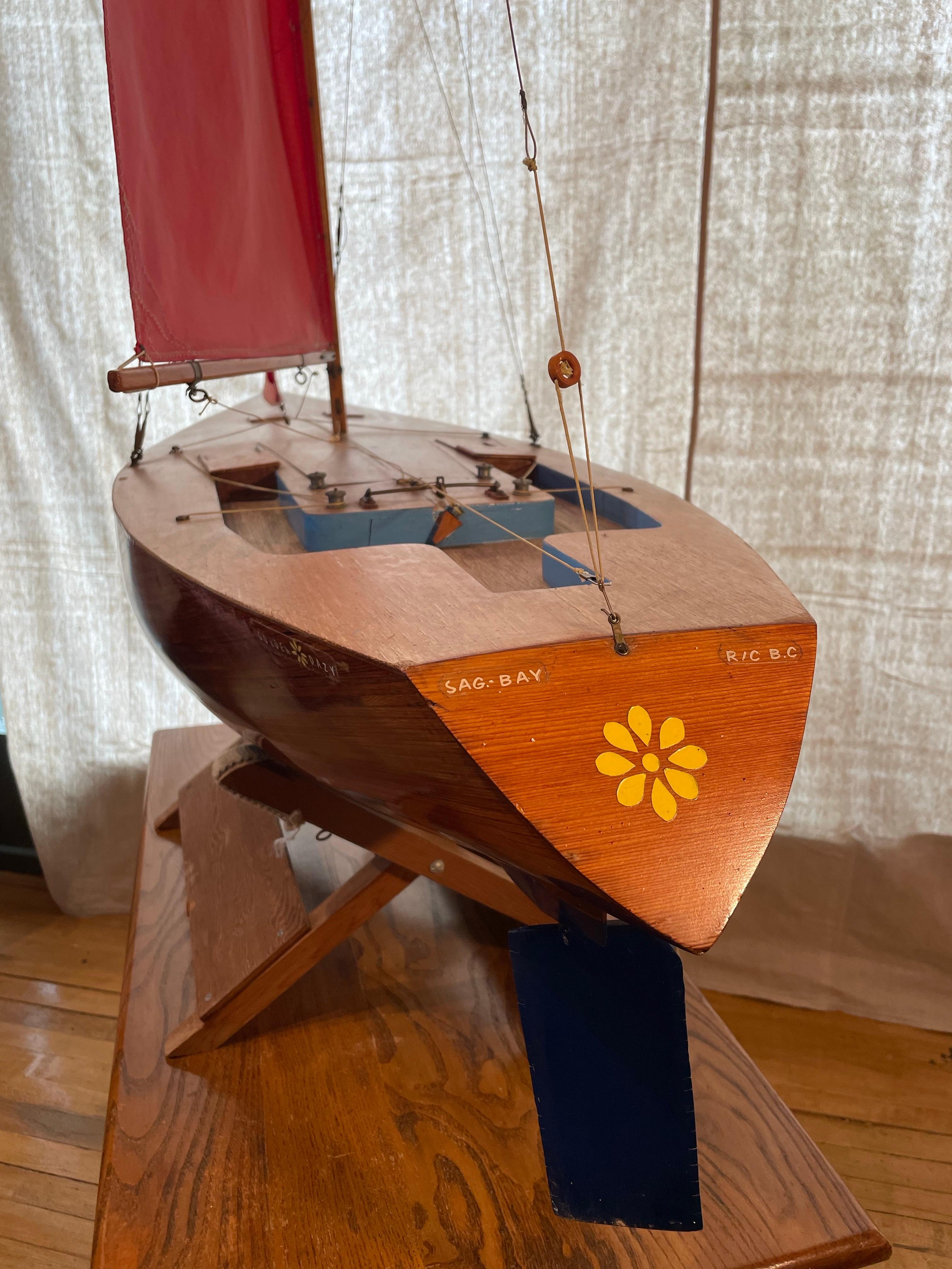 Este llamativo yate estanque hecho a mano a mediados de siglo ofrece una hermosa fusión de diseño náutico y presencia escultórica. Esta gran maqueta de velero, fabricada por expertos en madera noble barnizada, con el casco pintado de azul intenso y