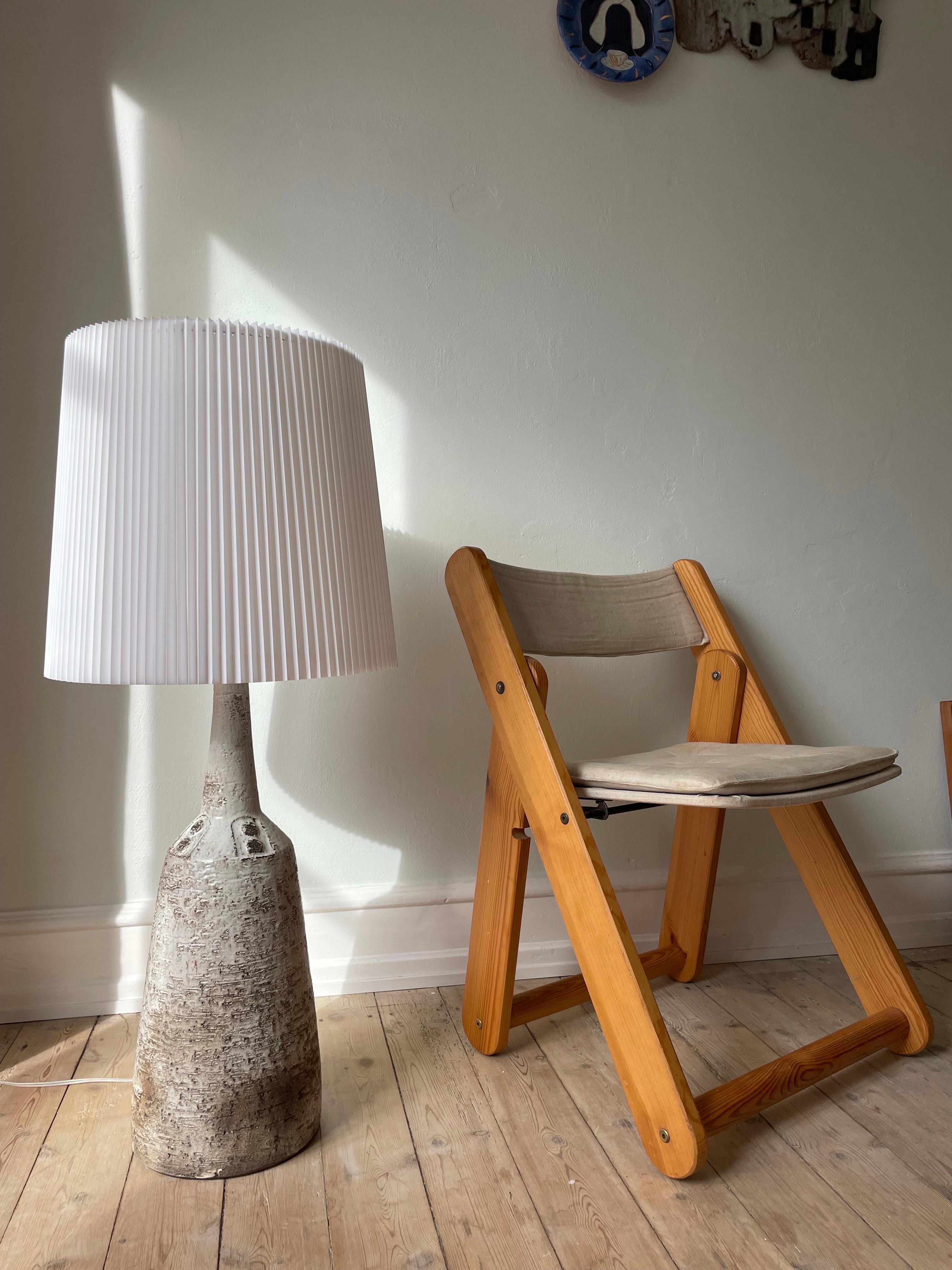 Tall, imposing brutalist Scandinavian modern handmade chamotte ceramic floor or table lamp. Organic color mix glaze in white, grey and cedar on the rustic wide base bottle shape with circular hand-carved graphic relief decor around the slender neck.