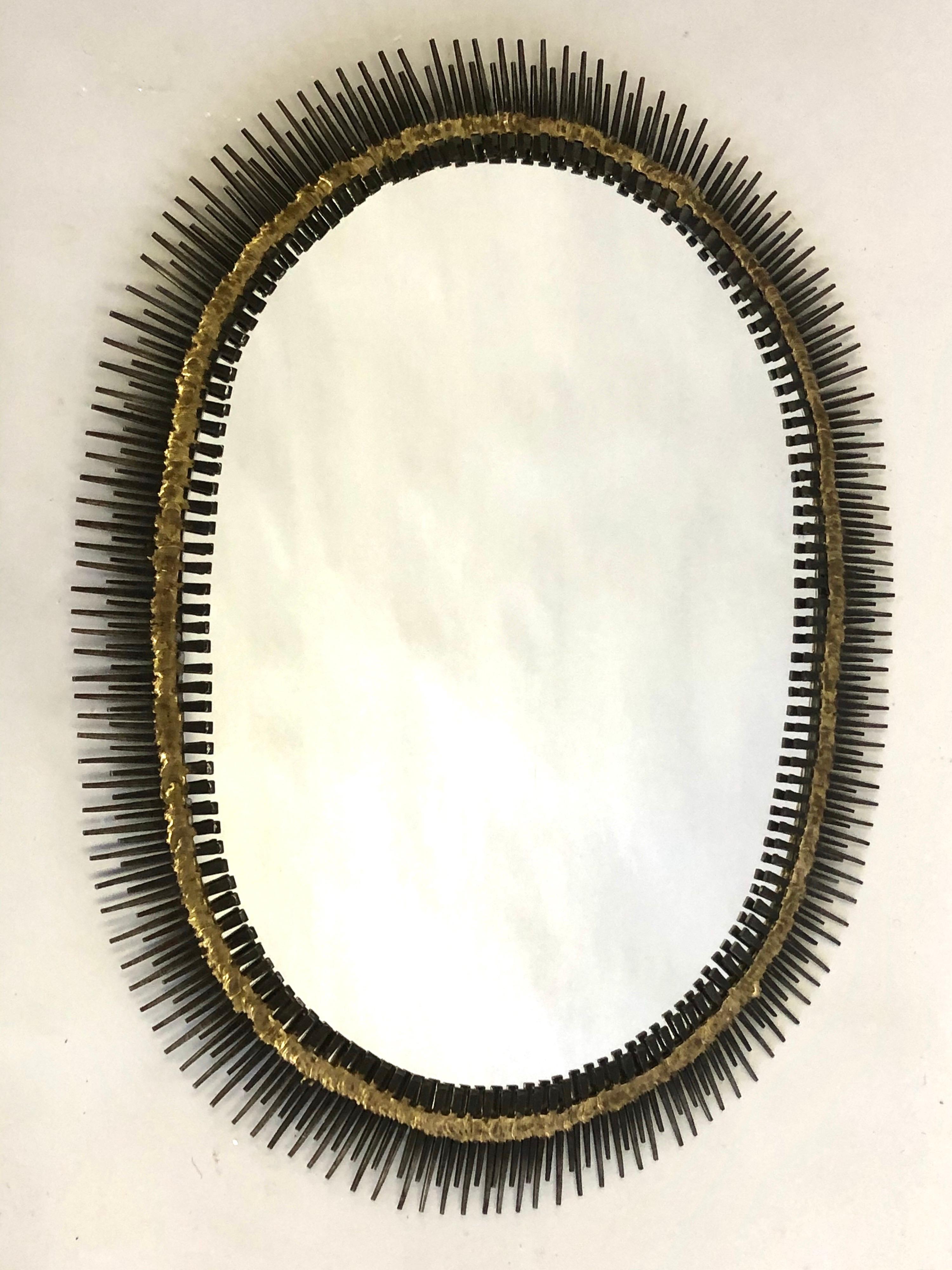Elegant Handmade Mid-Century Modern Craftsman wall mirror or wall mounted sculpture in an oval sunburst form by the French Canadian artist, Bela. The piece has a striking and refreshing quality with it's oval form and dynamic materials and its hand