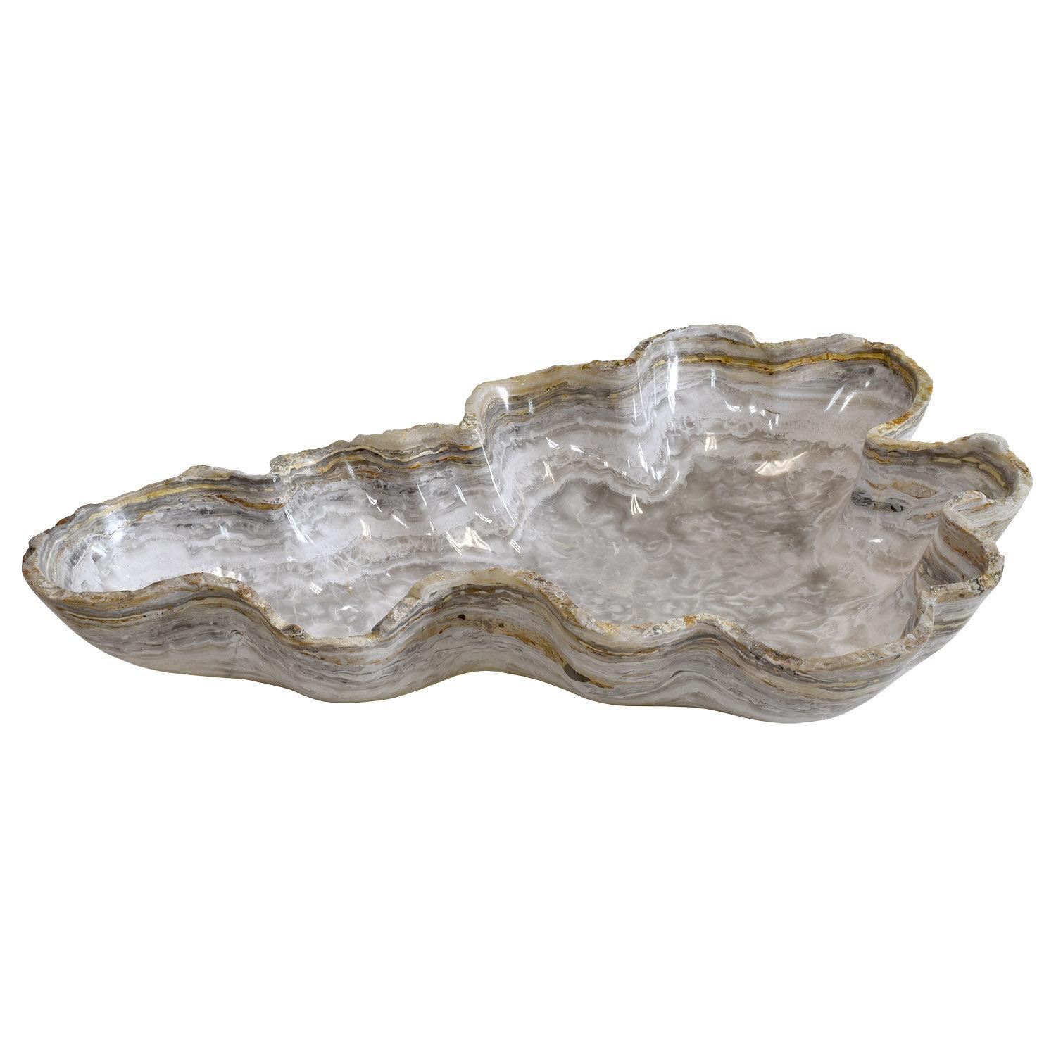 Handmade in Mexico
Carved from a single piece of onyx
One of a kind
Dimensions: 23 x 17 x 4.25 in. / 60 x 43 x 10 cm

A fluted, almost to the point of frilly, organic “oyster” shaped of vessel from naturally colored stone with the mineral