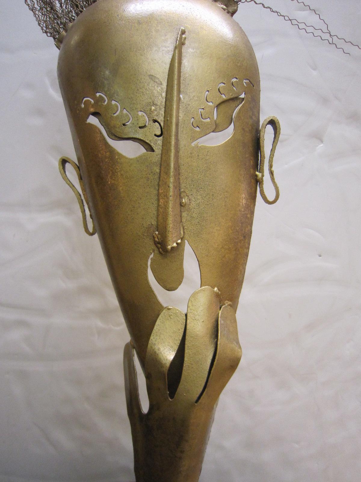 A large steel statue of a hand cut figural mask with lively wire hair in a mottled dark antique gold / brass painted finish with a slightly textured surface.
Wiener Werkstatte, Hagenauer style with decorative eyelashes, exotic shaped eye cut-outs,