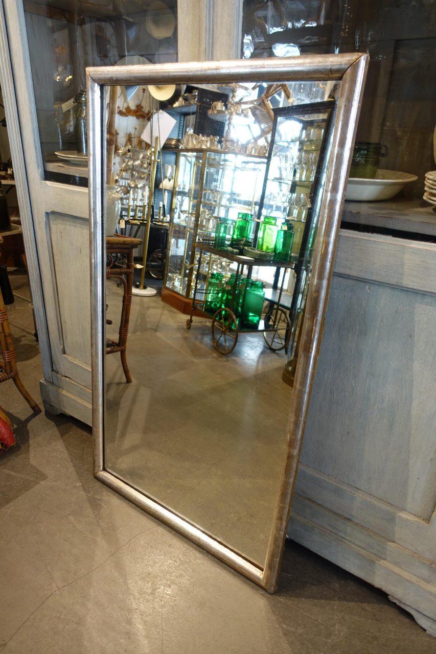 Large and handsome antique French mirror from circa 1880-1890, surrounded by a charming sleek and plain simple rounded silver frame. Gorgeous patina. The mirror still retains its original silver sheet layer on the frame and the old mercury mirror