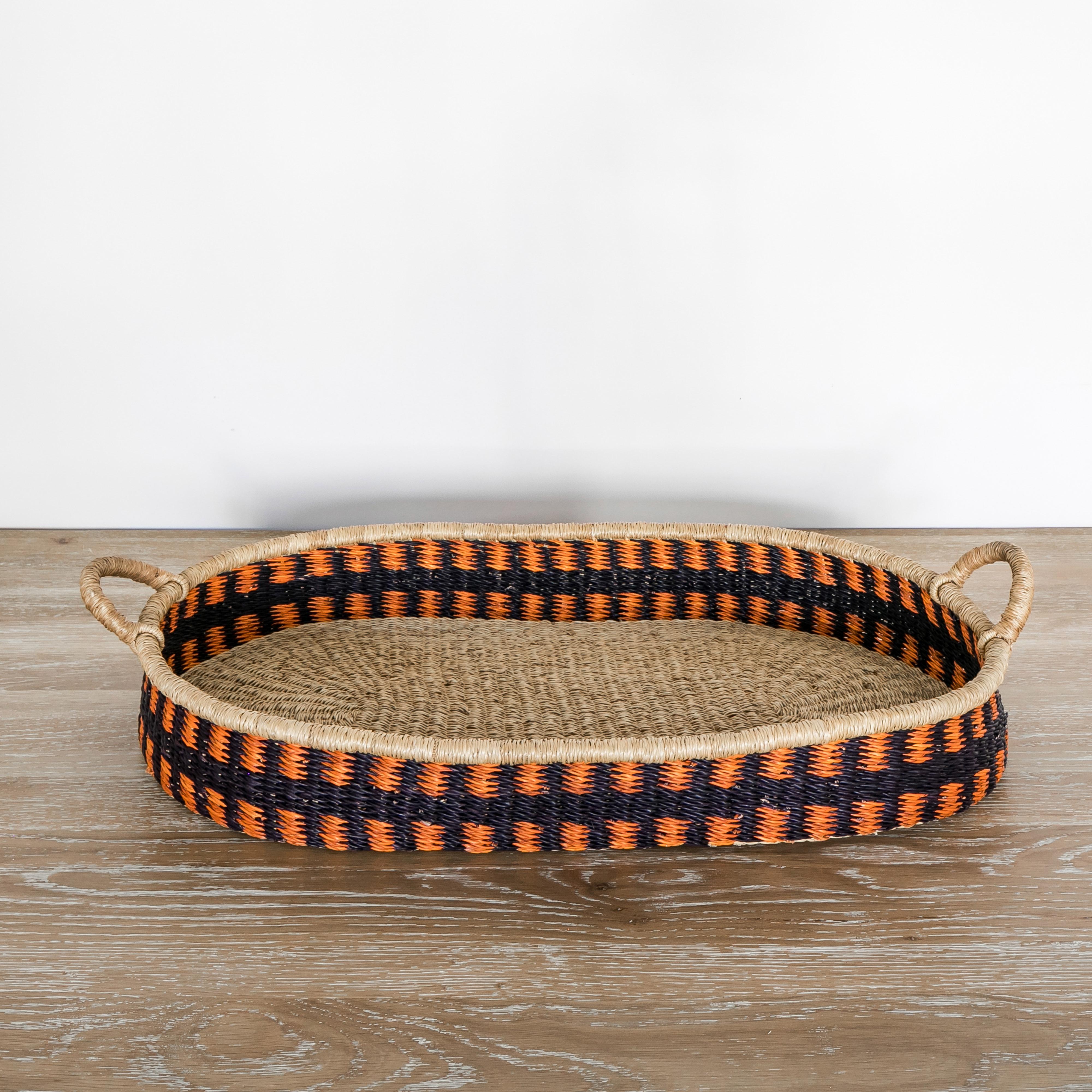 Large Handwoven Oval Basket with Decorative Color Pattern. Expertly women by and using elephant grass. It is light and easy to move with the handles. Use for decor or to organize your space. The attractive orange and blue color pattern pairs well