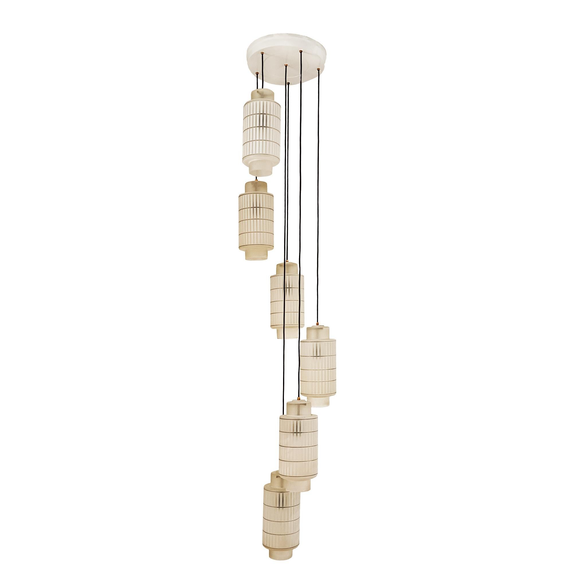 Grande lampada a sospensione con 6 globi di vetro smerigliato inciso all'acido e decorato con linee nere. Un ingegnoso sistema per rimuovere la vetreria. Piastra superiore in lamiera laccata bianca. Fili di plastica nera.

Italia 1950-60