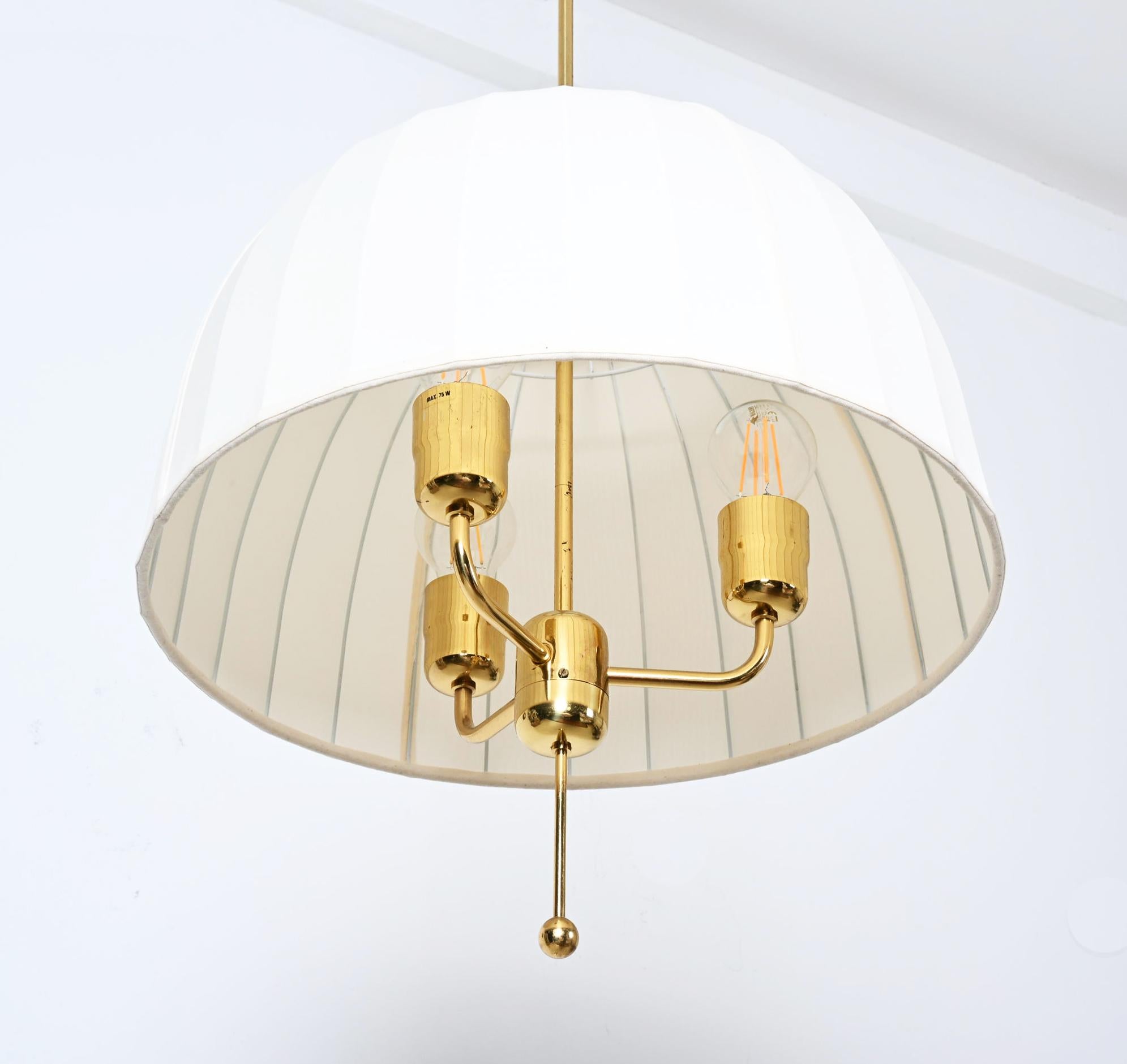 Raro pendente da soffitto con nuovo paralume in seta thailandese in tessuto bianco e crema su montatura in metallo laccato bianco. 
Modello Caroline T549/3 in ottone progettato nel 1963 da Hans-Agne Jakobsson. La lampada e il paralume sono